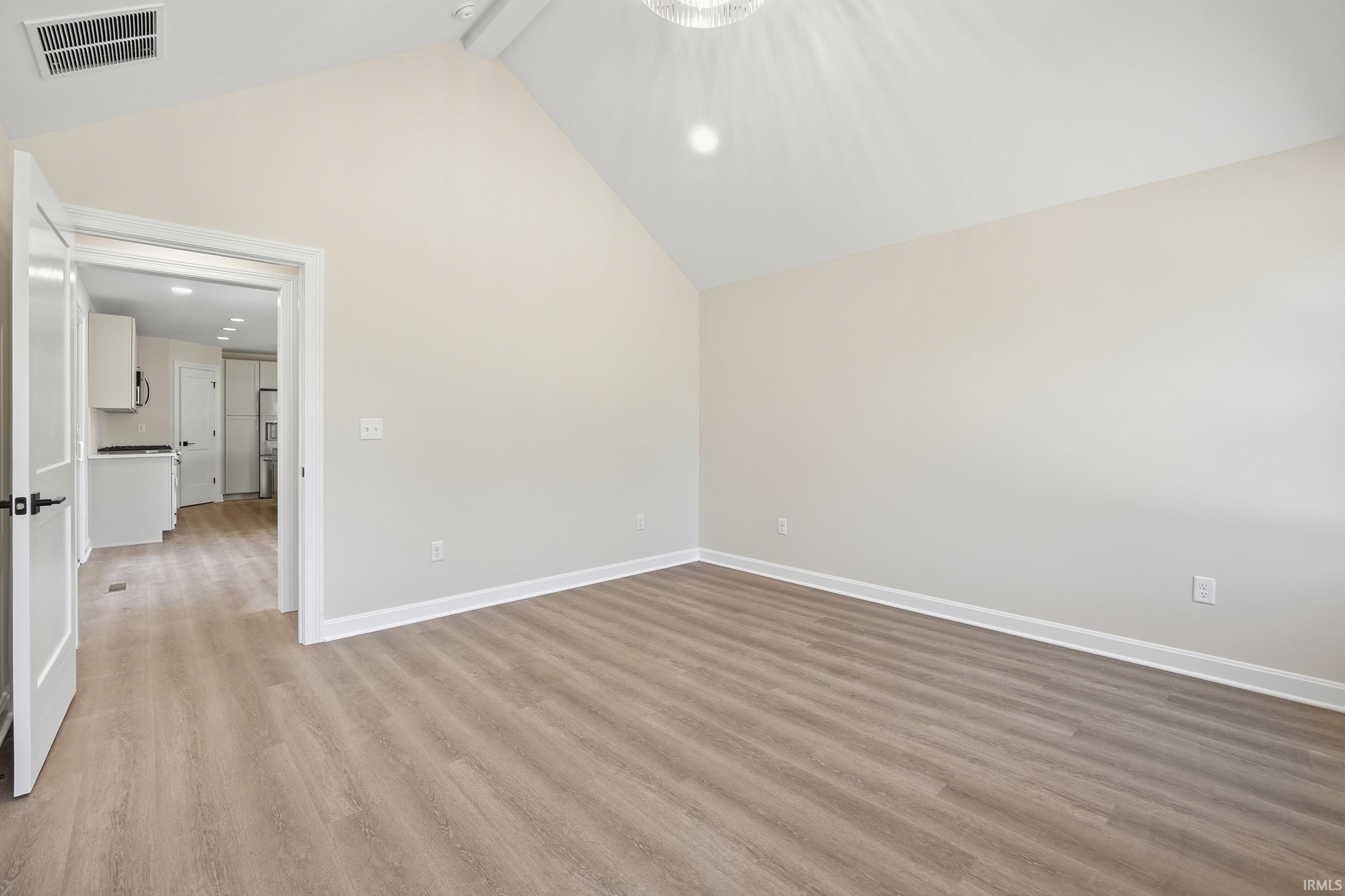 Spacious room with vaulted ceilings, recessed lighting, and wood-finish flooring
