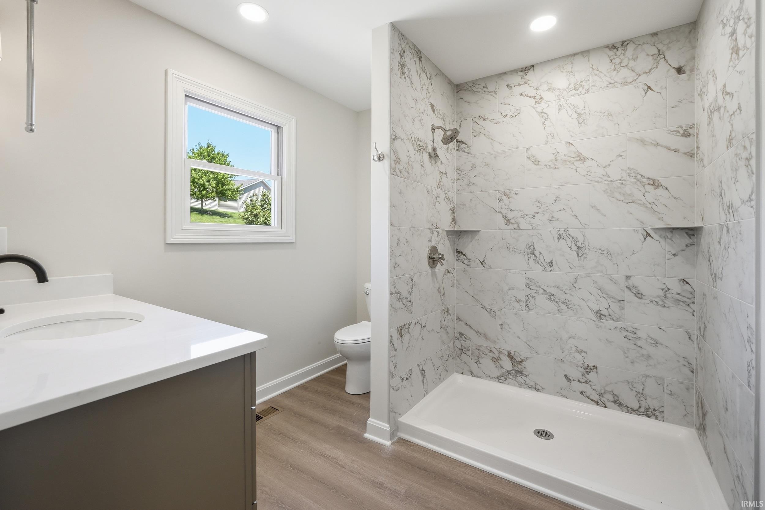 Bathroom featuring a walk-in shower with marble-look tile surround and two built-in shelves