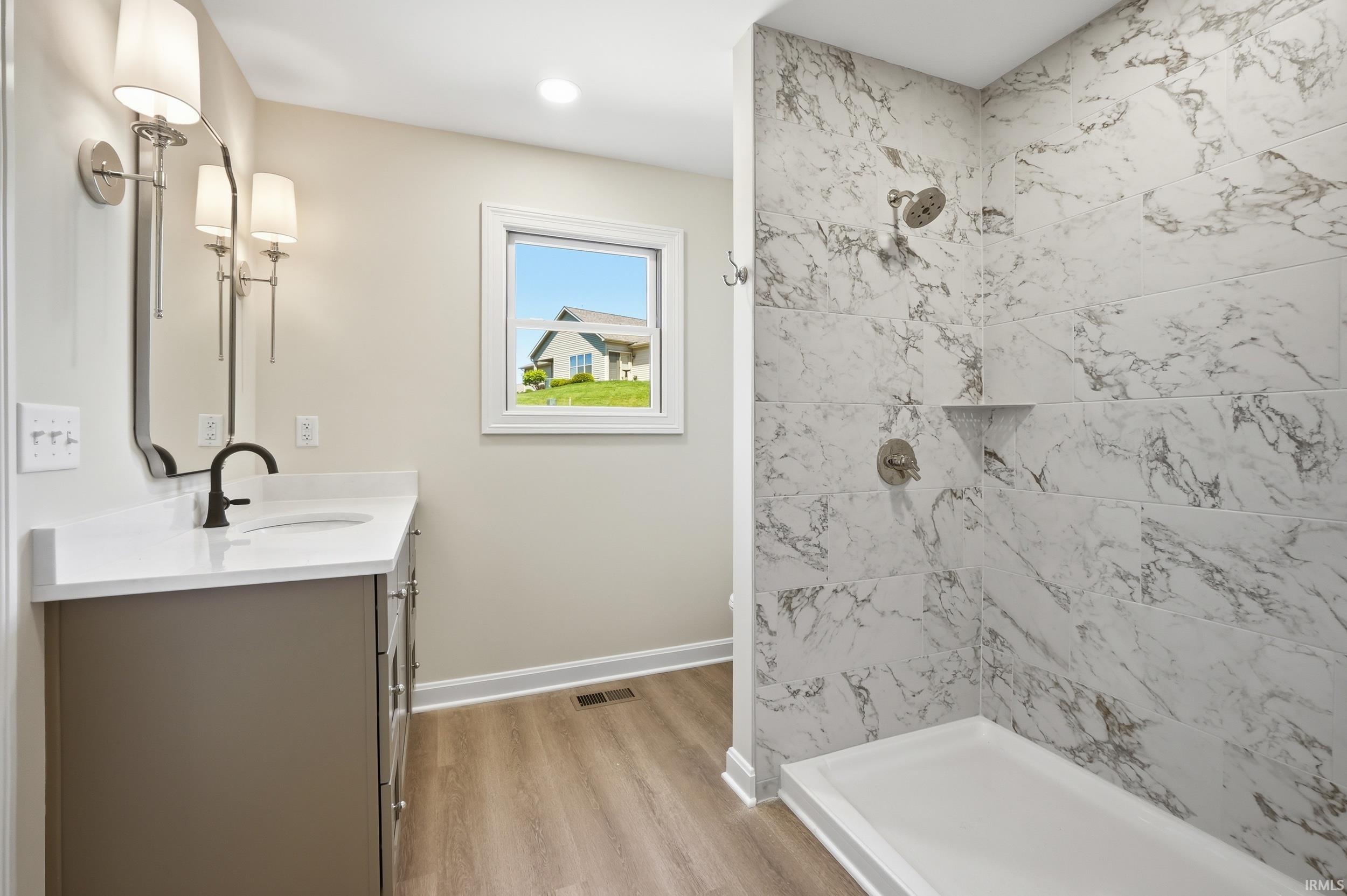 Contemporary bathroom featuring a spacious shower with marble-look tile surround and a built-in niche