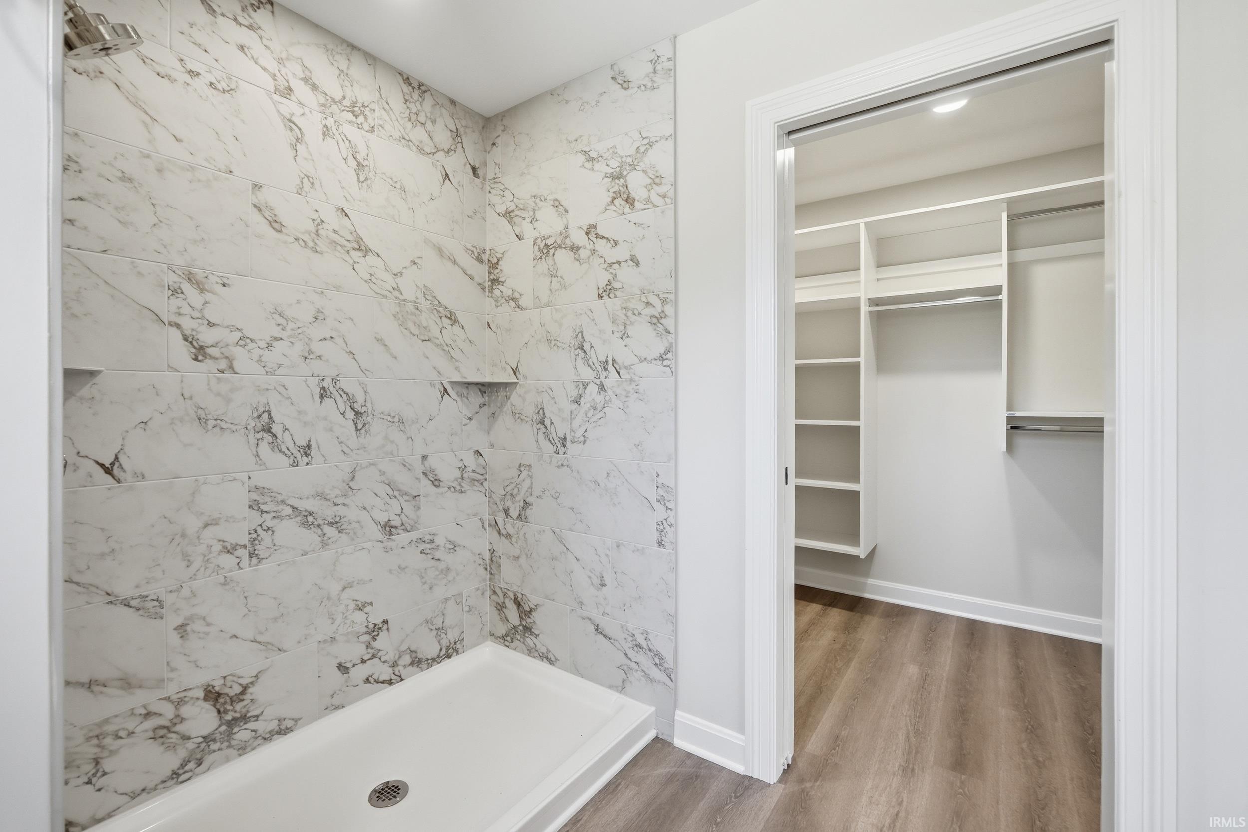 Walk-in shower with marble-look tile surround and two built-in niches