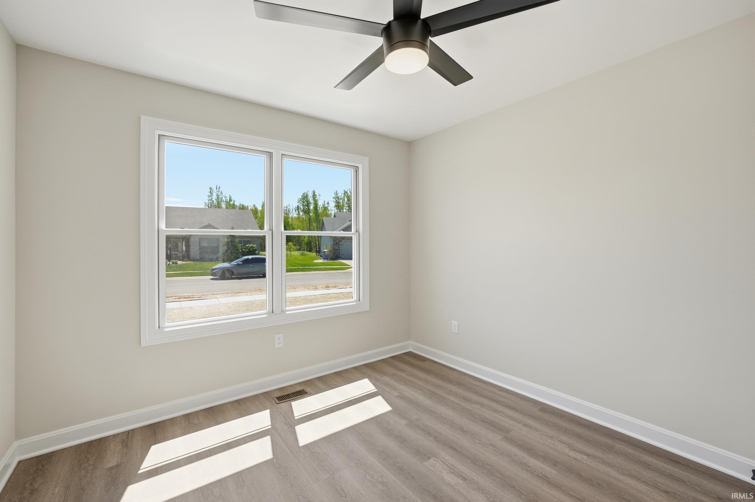 Bright interior space featuring a double window, wood-finish flooring, and a ceiling fan with integrated lighting