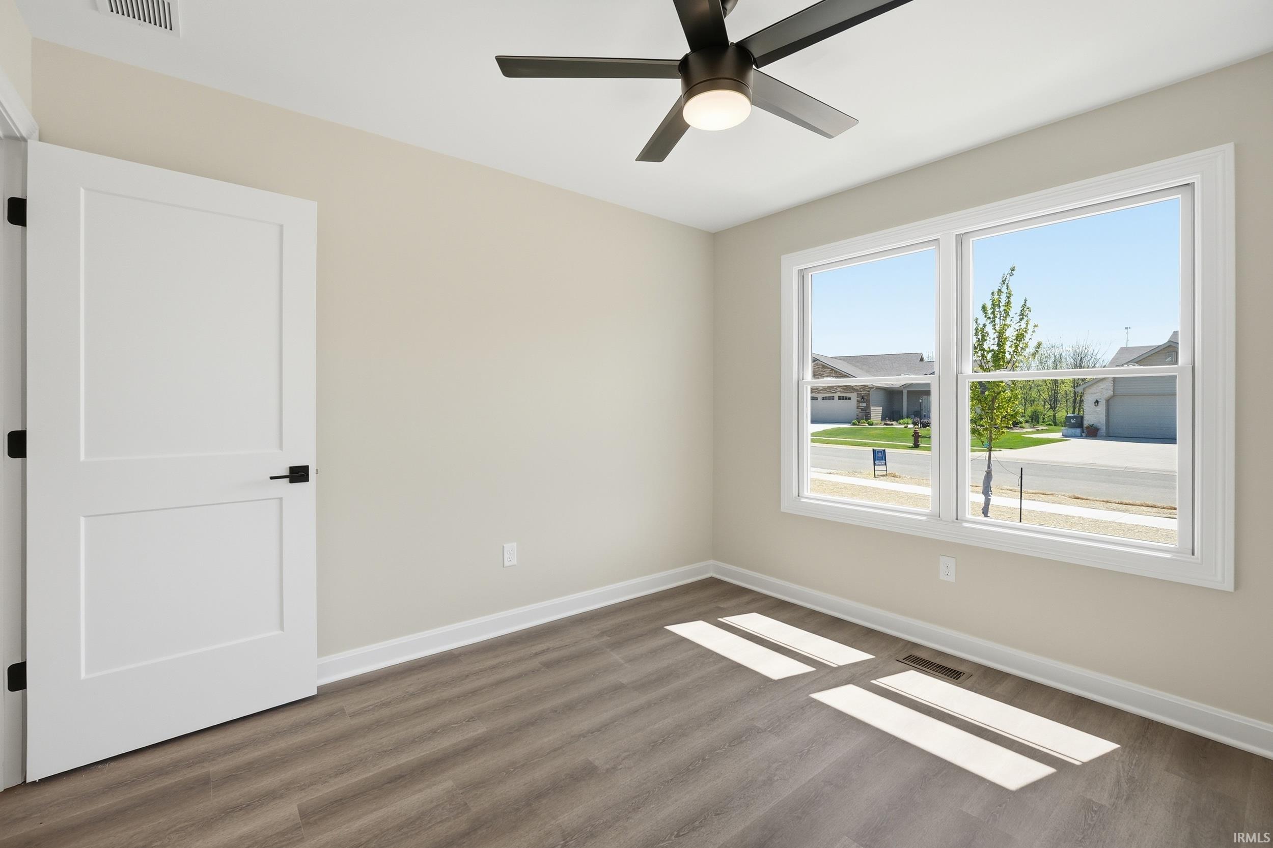 Room featuring wood-finish flooring, light-colored walls, and a modern ceiling fan with integrated lighting