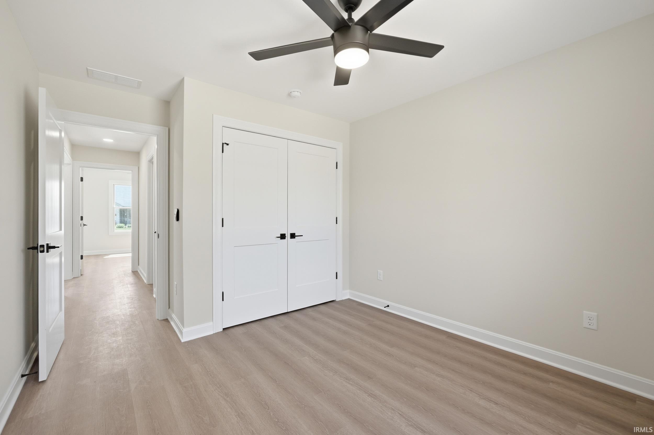 Bedroom featuring wood-finish flooring, a contemporary ceiling fan with integrated lighting, and a double-door closet with matte black hardware