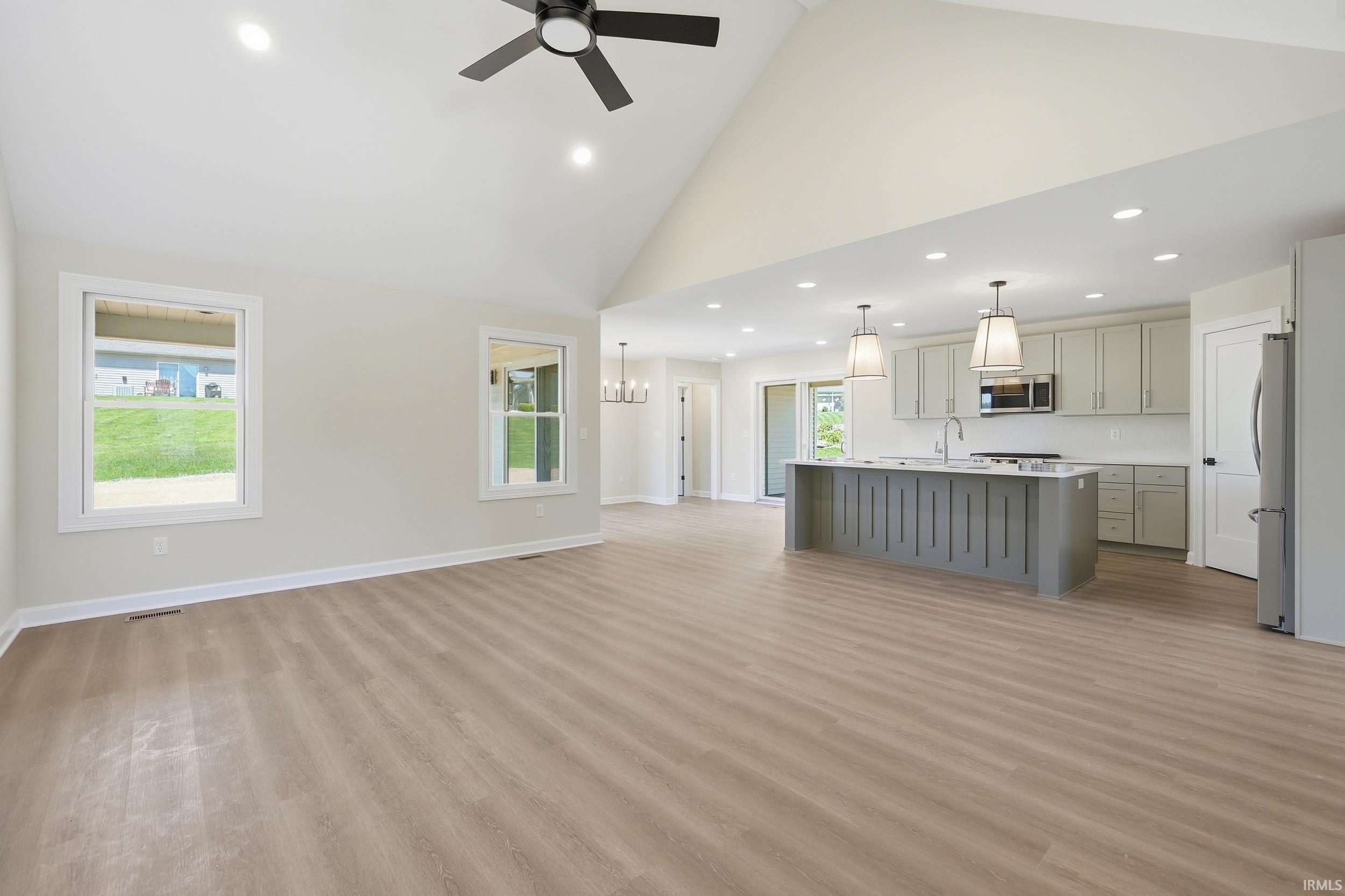 Expansive open-concept living space featuring vaulted ceilings, wood-finish flooring, and recessed lighting
