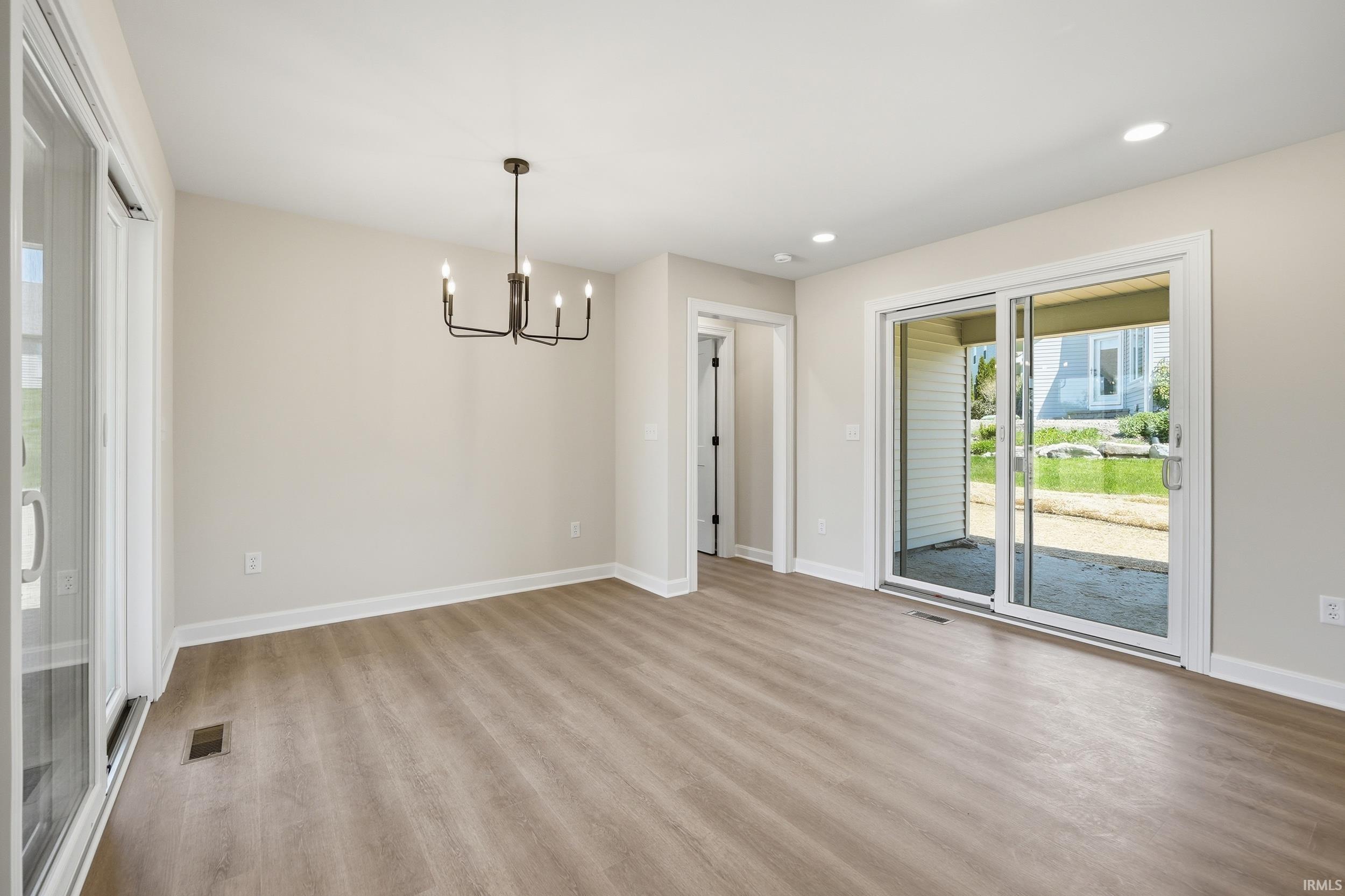 Open-concept room featuring light wood-finish flooring, recessed lighting, and a contemporary chandelier
