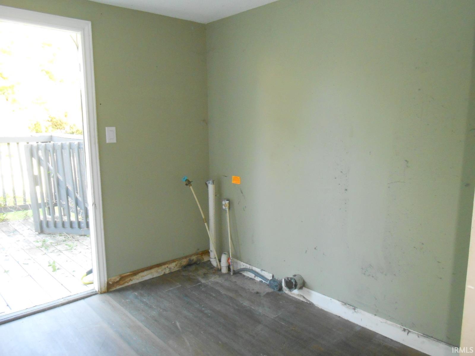 Room featuring light green walls, wood-finish flooring, and white trim