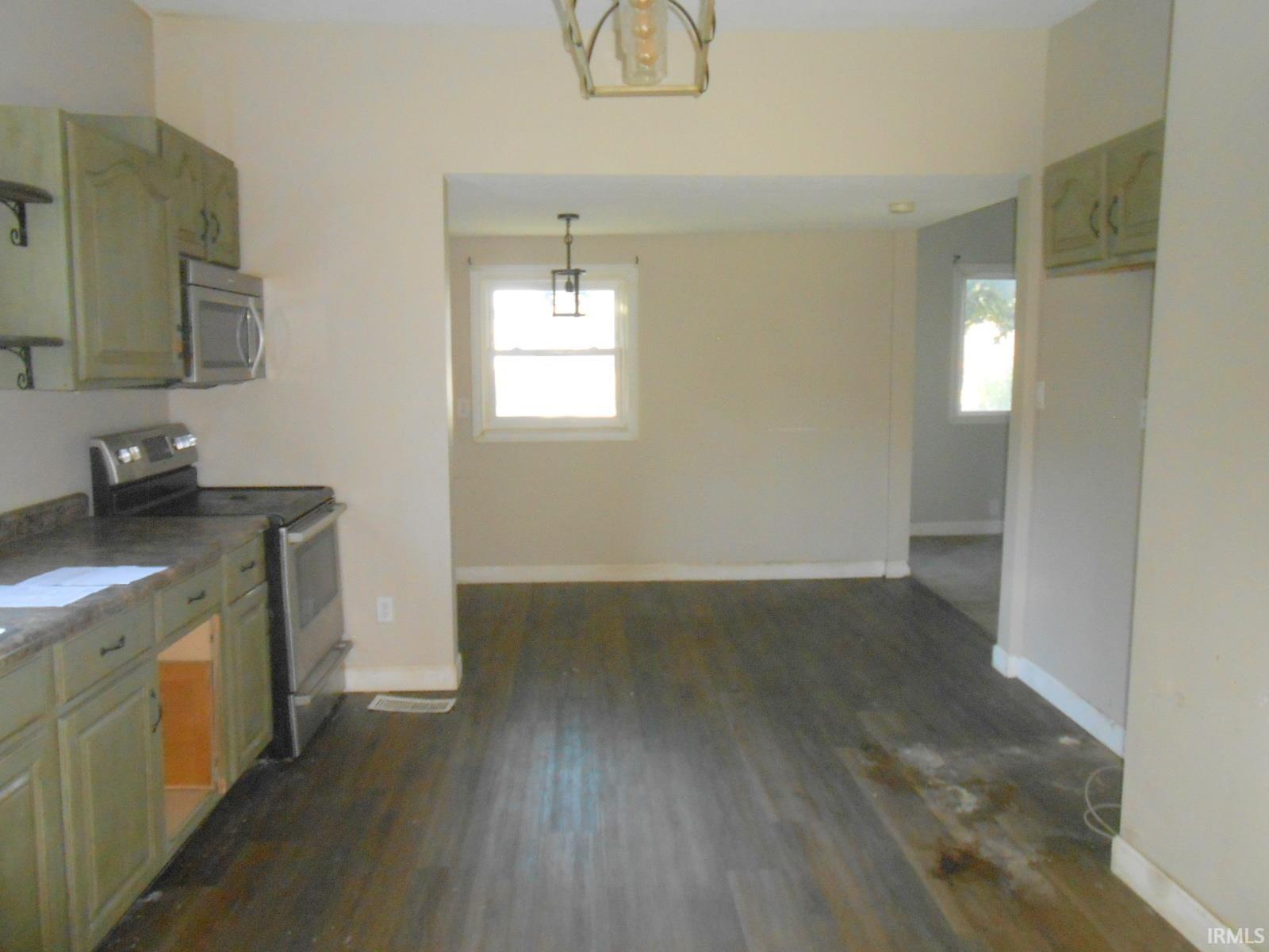 Kitchen space featuring wood-finish flooring, light-toned cabinetry, stainless steel range, and an over-range microwave