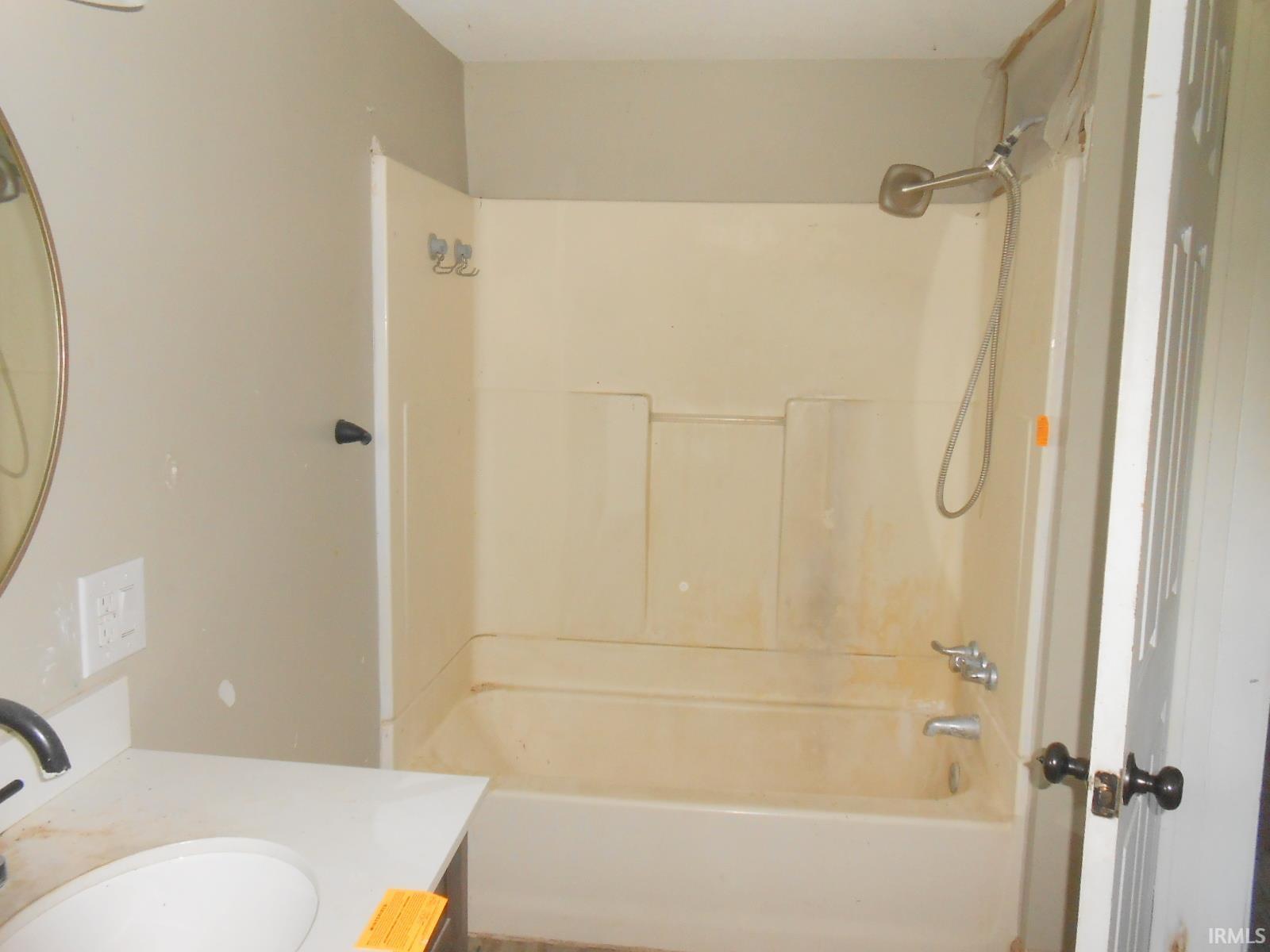 Bathroom featuring a white vanity with an integrated sink, a brushed nickel faucet, and a wall-mounted oval mirror