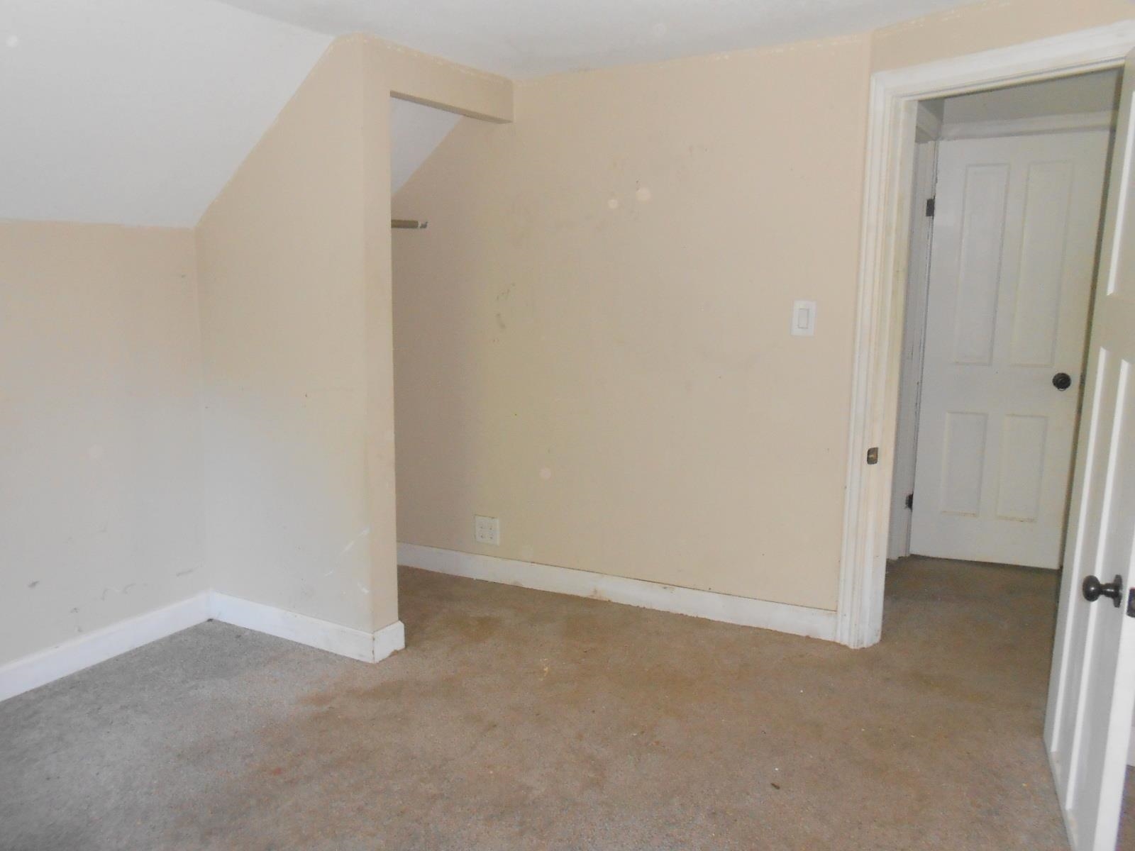 Neutral wall tones in this interior space featuring a partial sloped ceiling