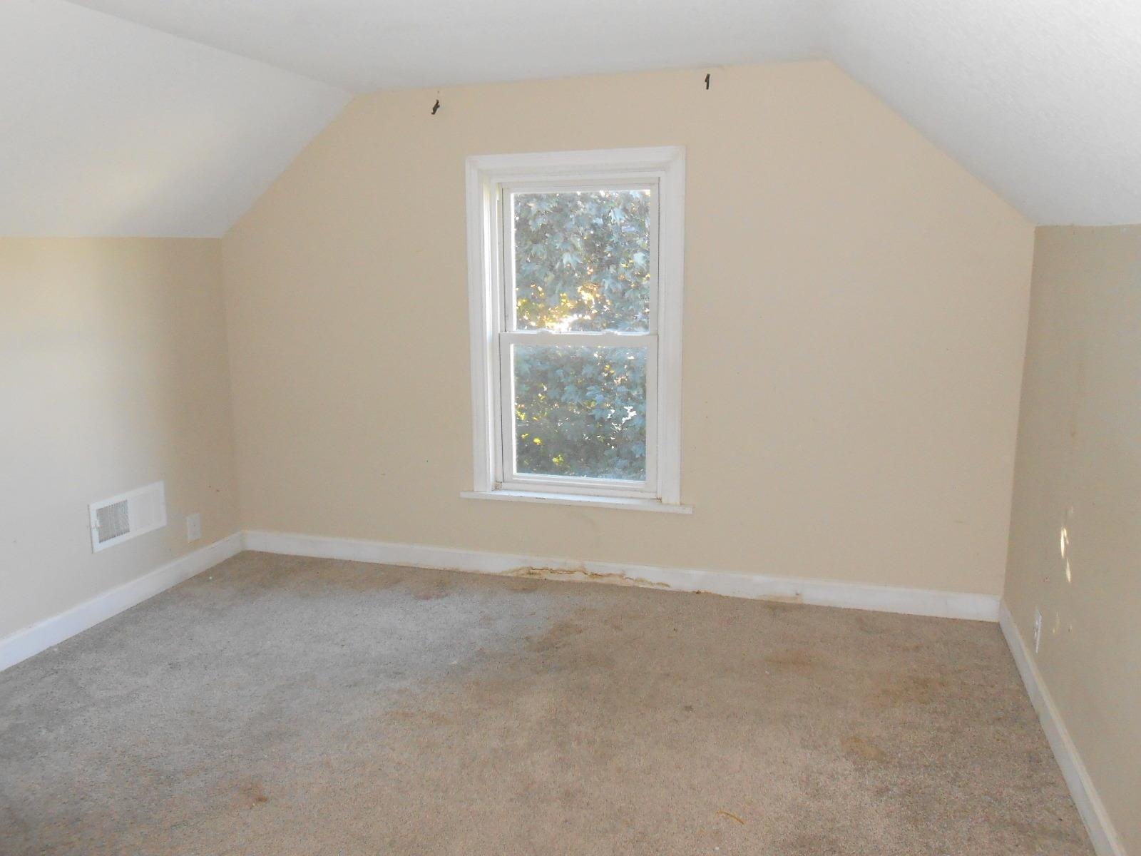 Carpeted room featuring a single window and sloped ceilings