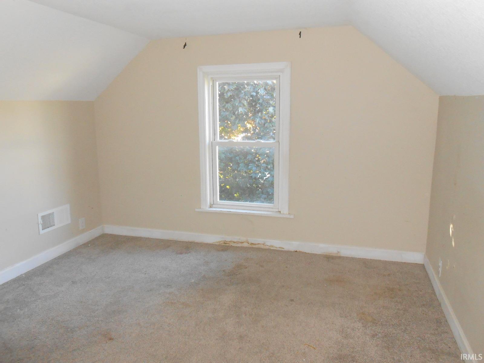 Carpeted room featuring a single window and sloped ceilings
