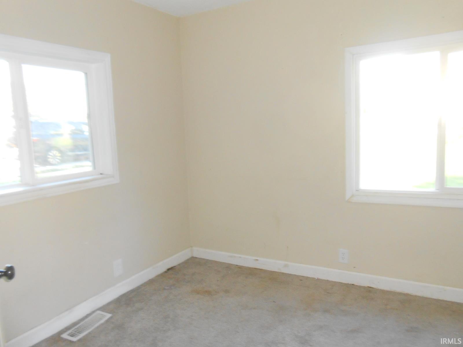 Room featuring two windows, neutral wall tones, and carpeted flooring