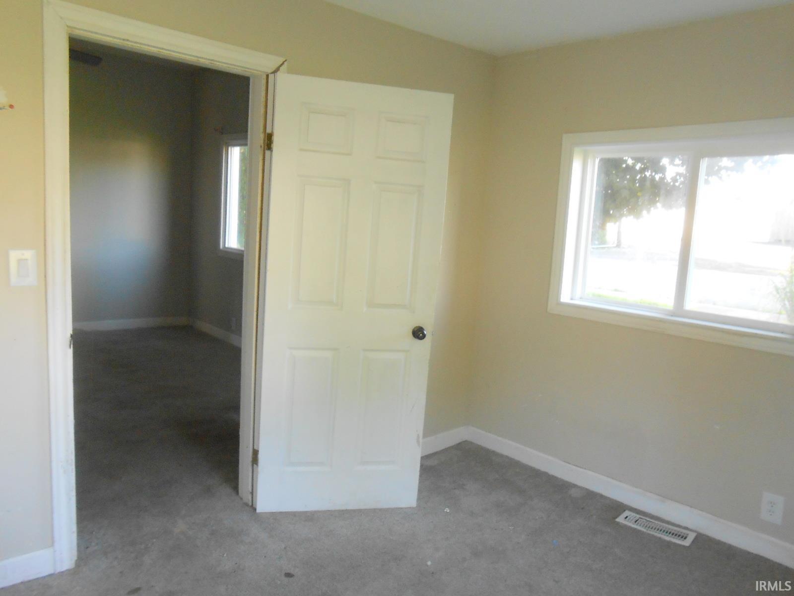 Carpeted room featuring a six-panel door, multiple windows with white trim, and baseboard molding
