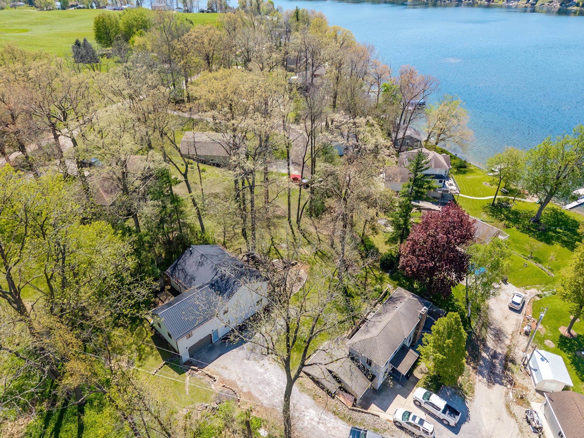 Aerial perspective highlighting multiple properties with mature trees and a substantial body of water