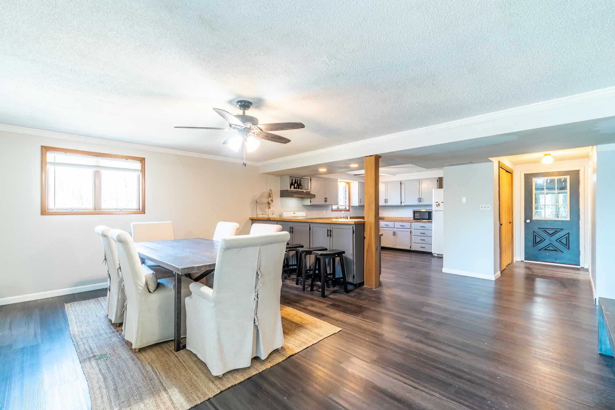 Open-concept living space featuring wood-finish flooring, a contemporary ceiling fan, and a neutral color palette