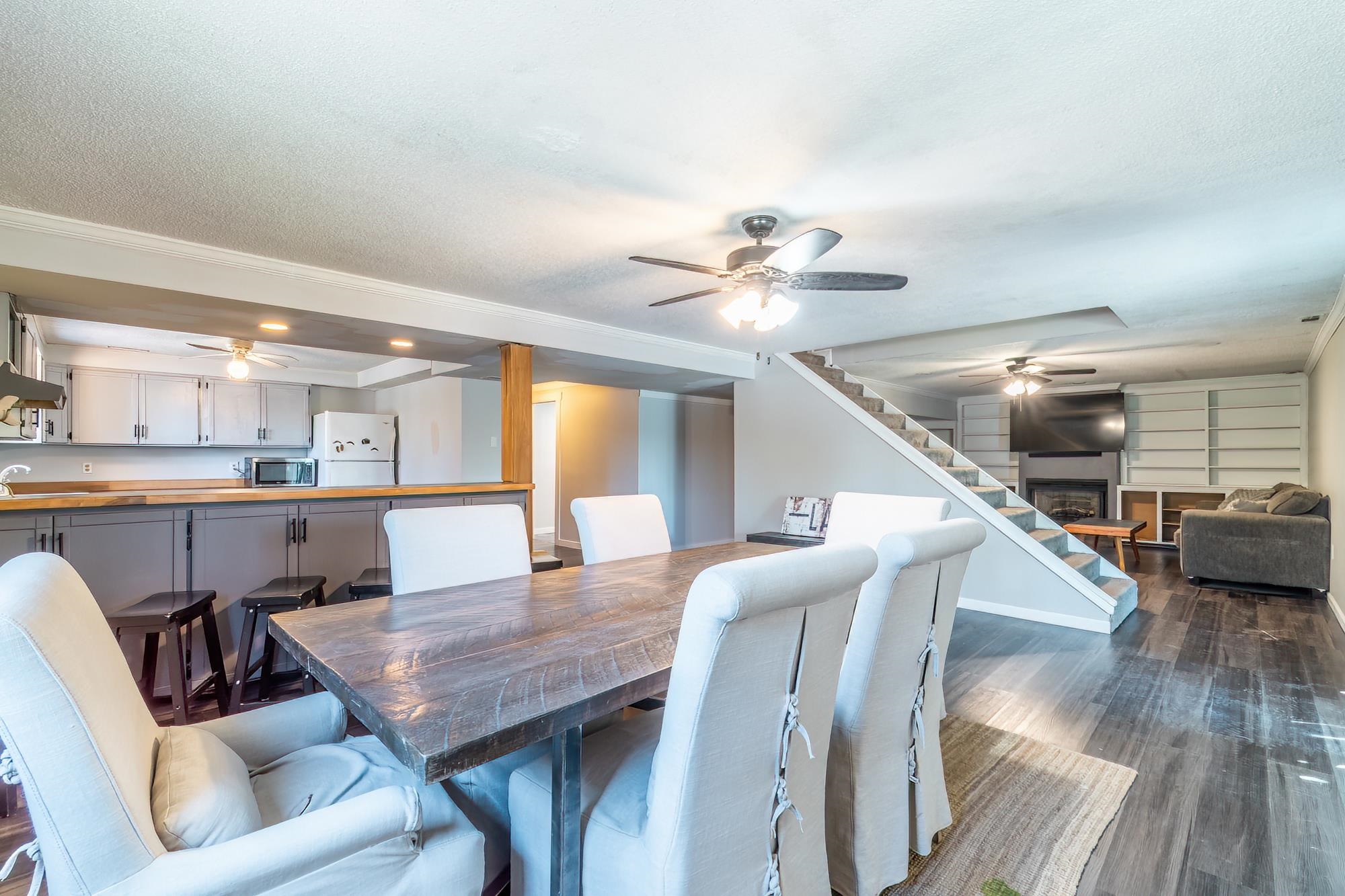 Spacious open-concept living area featuring wood-finish flooring, a contemporary fireplace, and built-in shelving