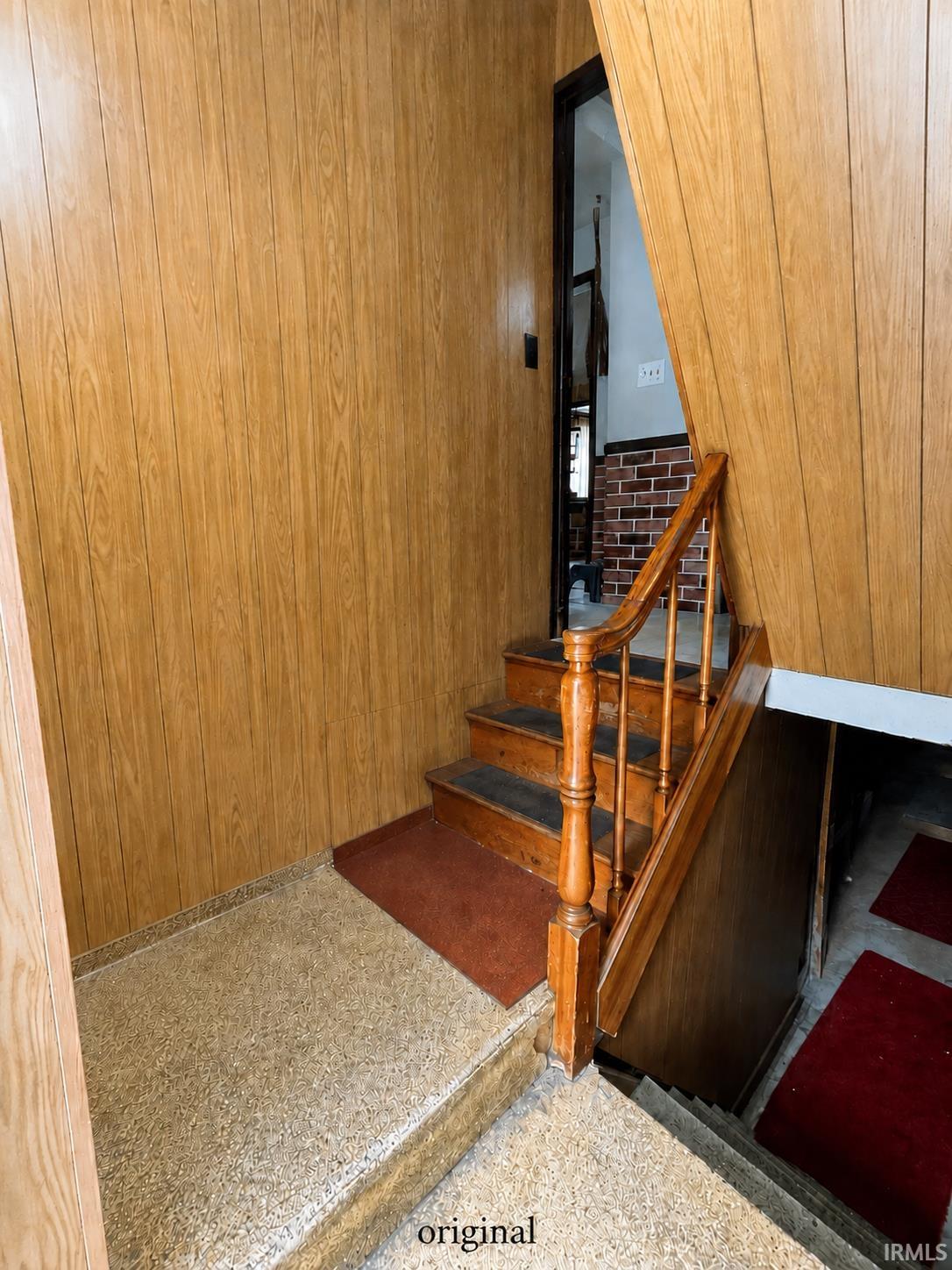 Stairwell featuring wood-finish paneling, an oak banister, and terrazzo-style flooring