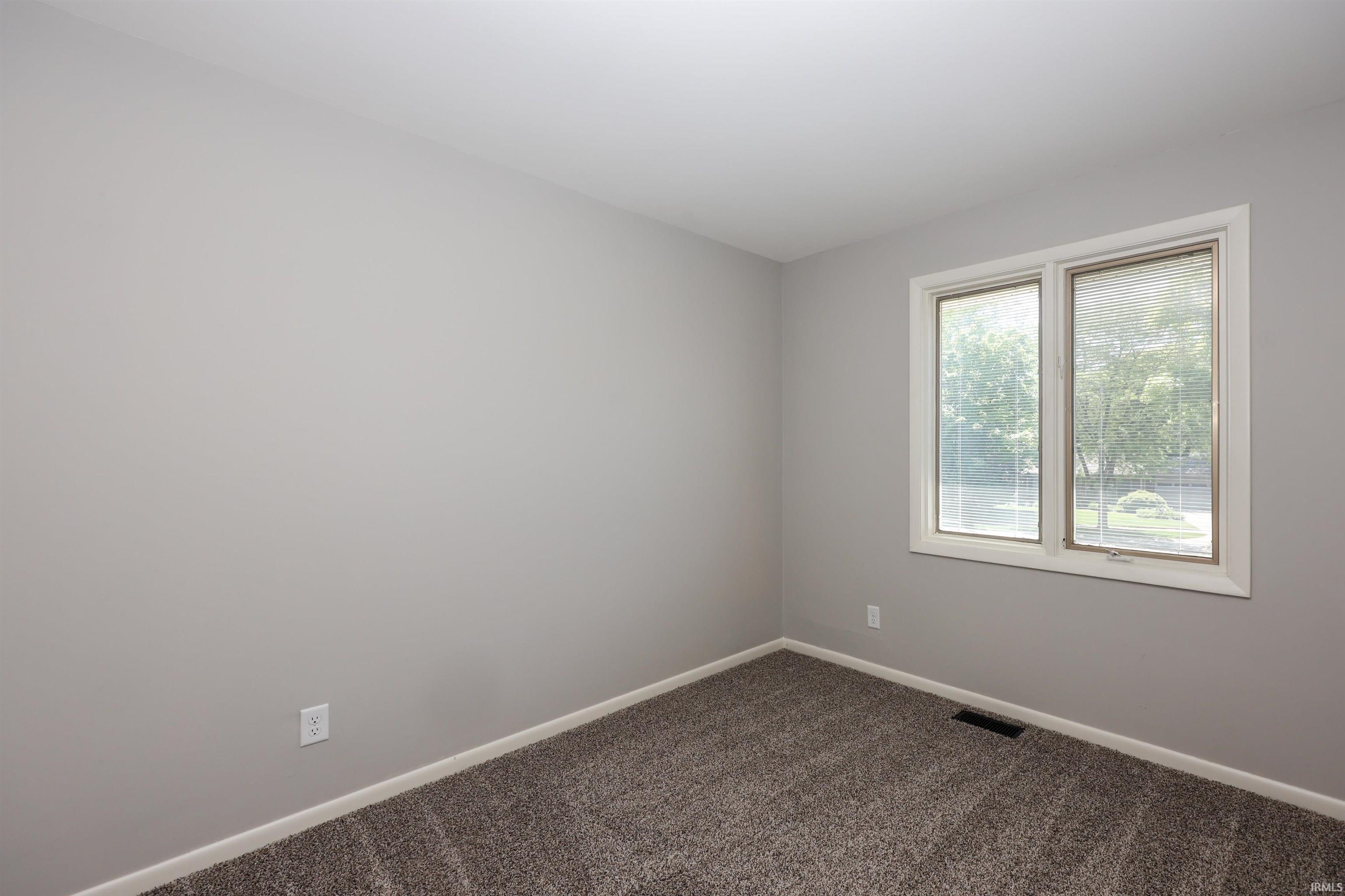 Neutral gray wall paint with white trim, gray patterned carpeting, and a dual-pane window