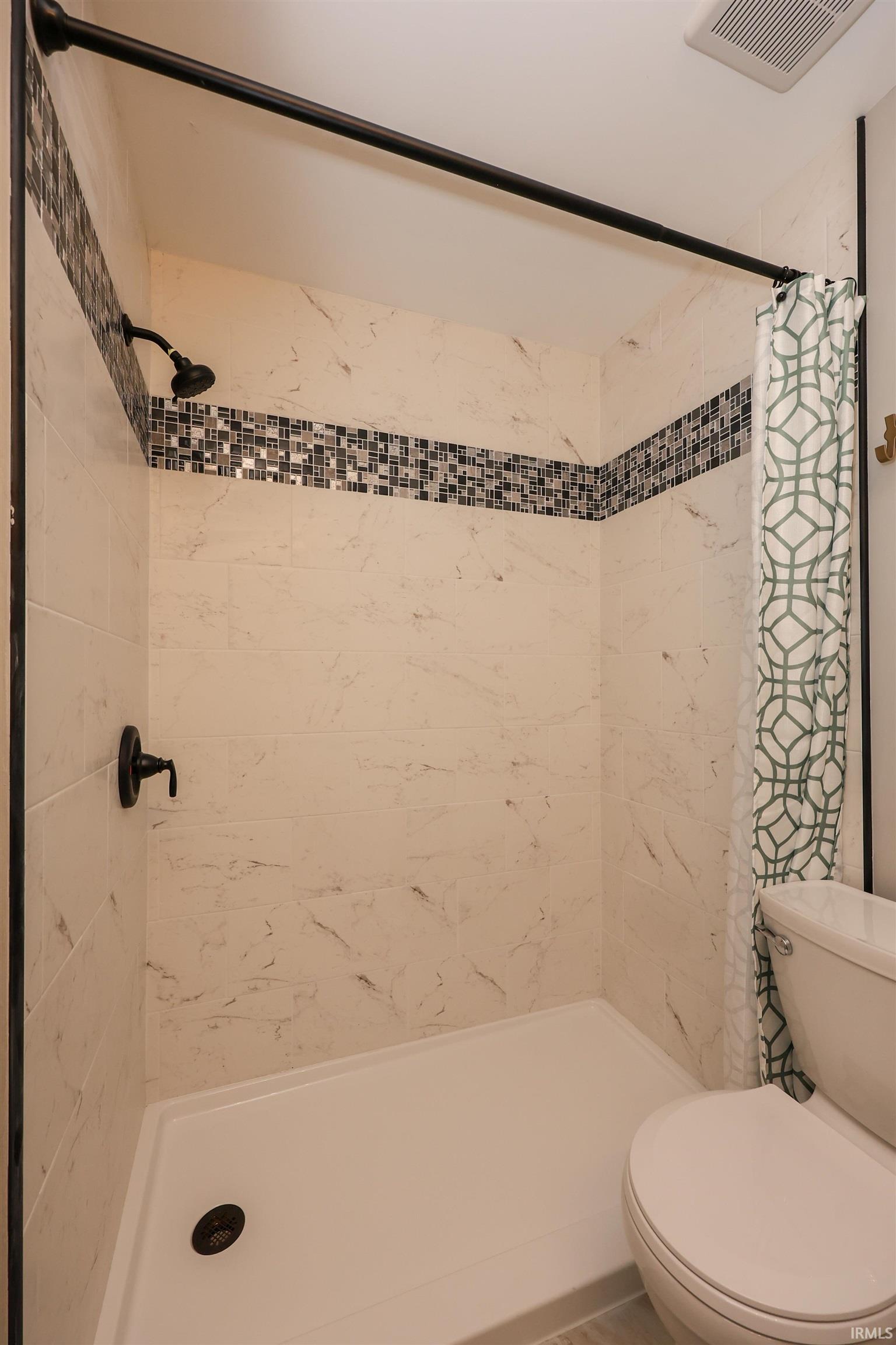 Shower stall with white and gray marble-look tile, mosaic accent band, oil-rubbed bronze shower fixtures, and white shower pan