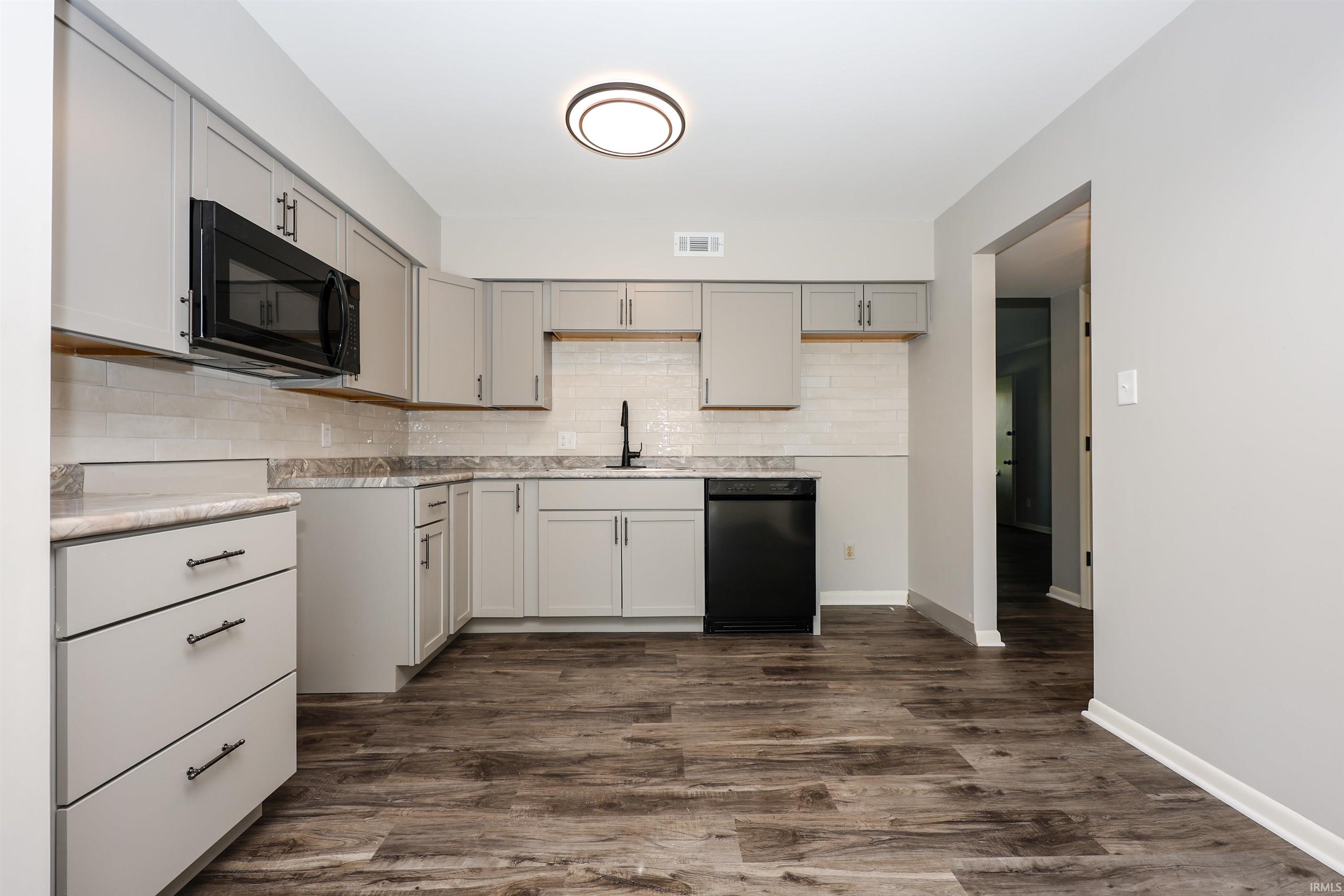 Kitchen featuring light gray cabinetry, dark wood-finish flooring, and a subway tile backsplash