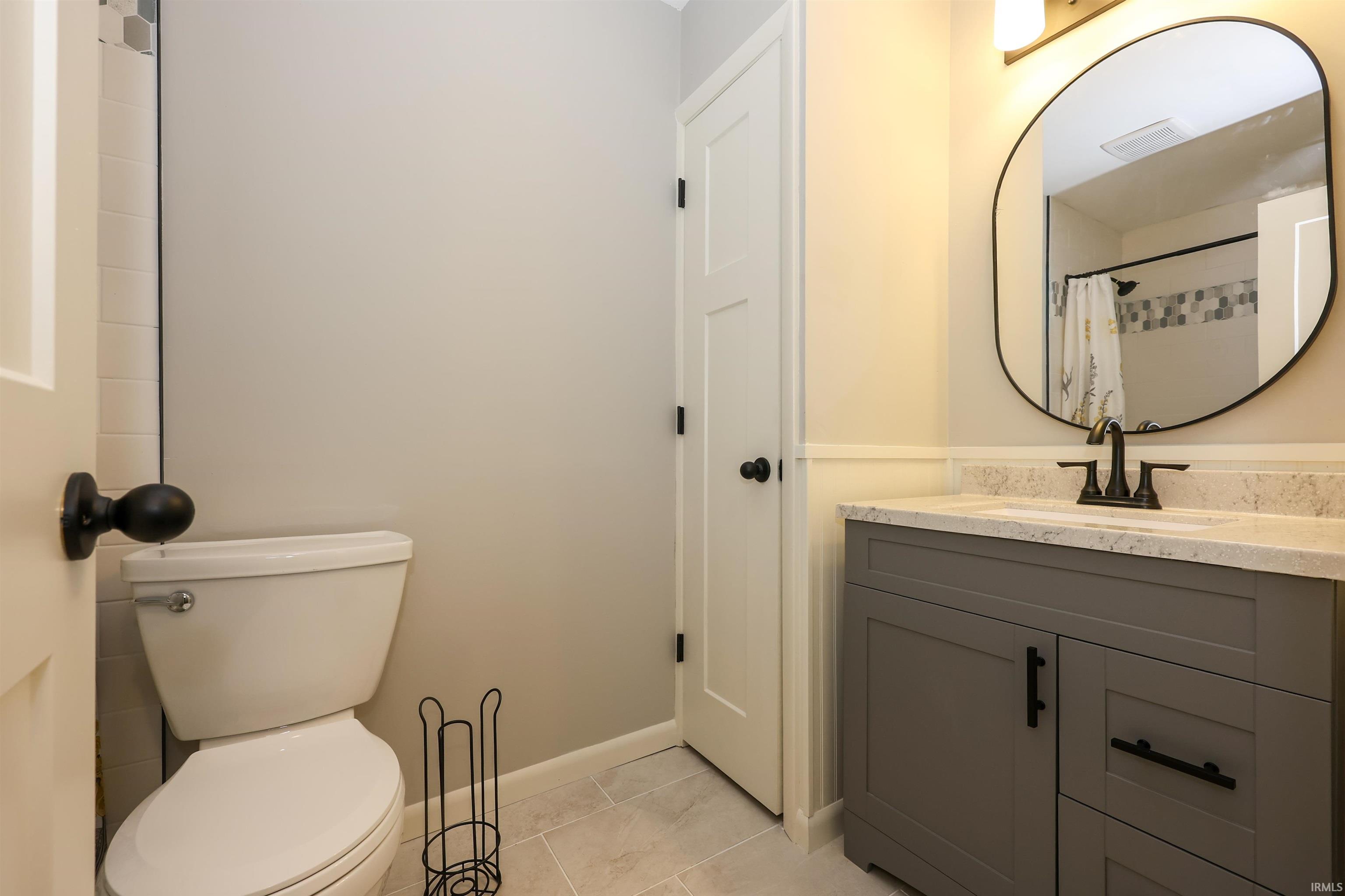 Bathroom featuring a gray vanity with a stone-finish countertop, undermount sink, and matte black faucet