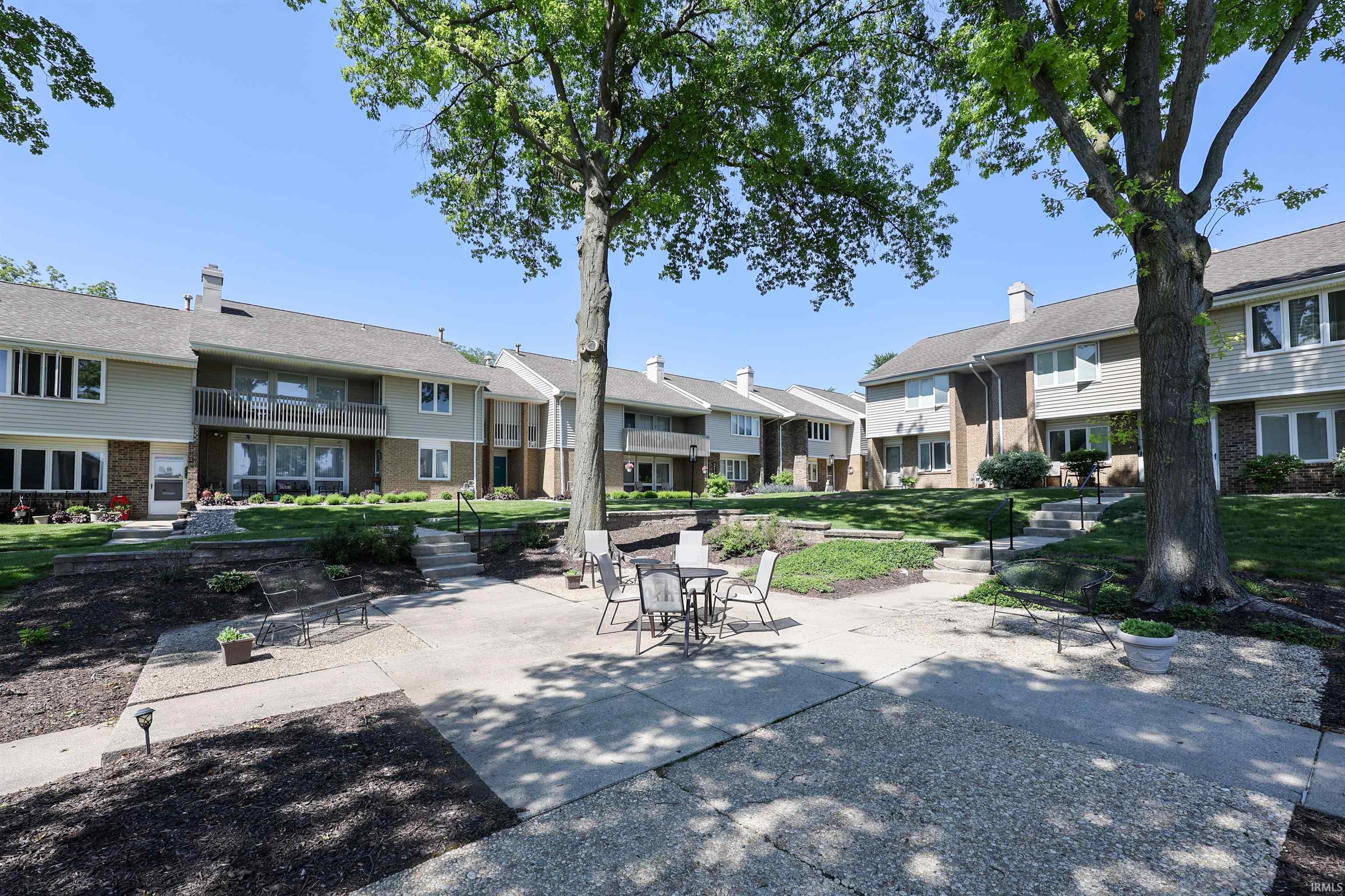 Community courtyard with mature trees, concrete patios, and established landscaping