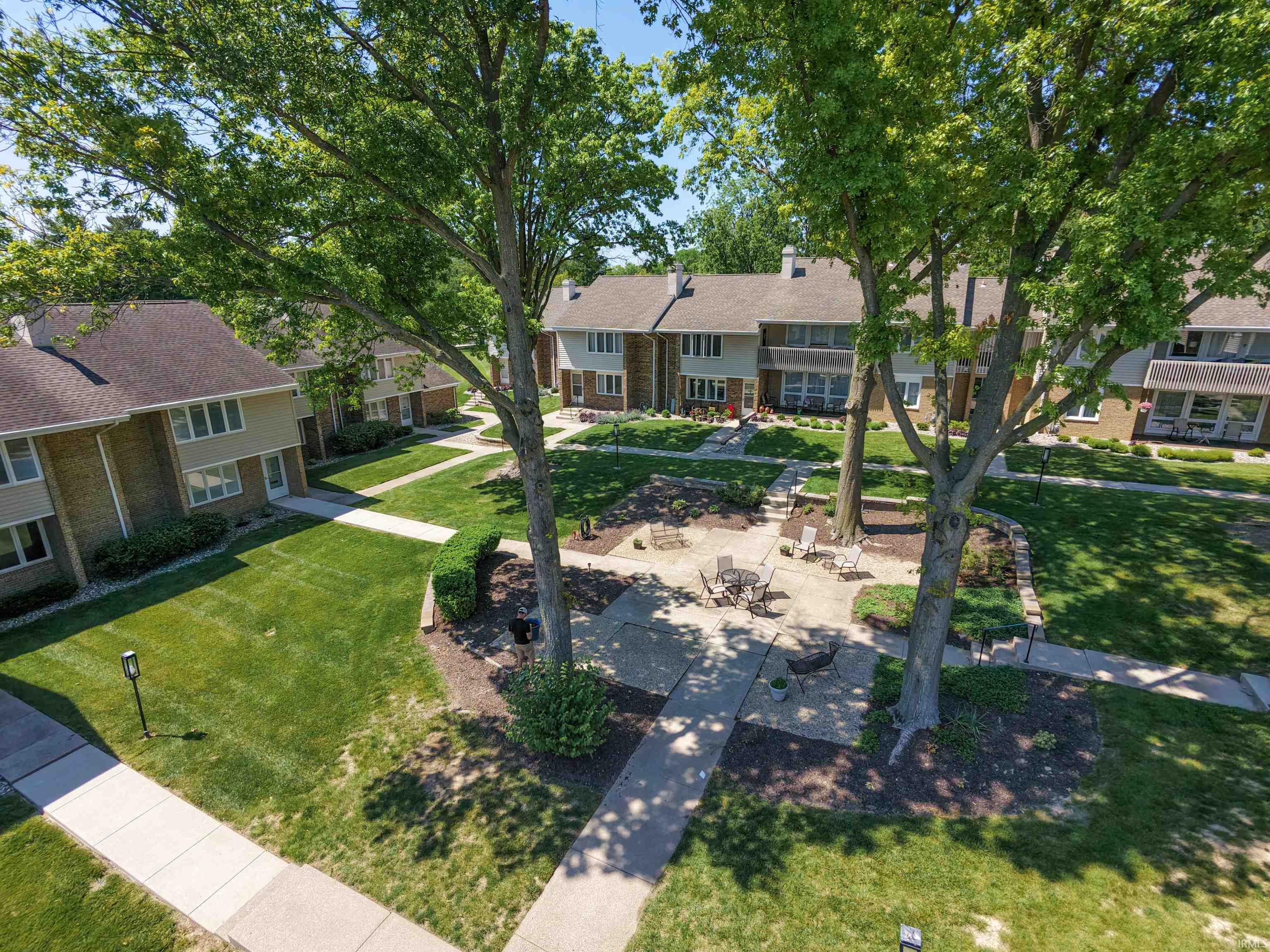 Well-maintained common area featuring paved walkways, mature trees, and manicured lawns