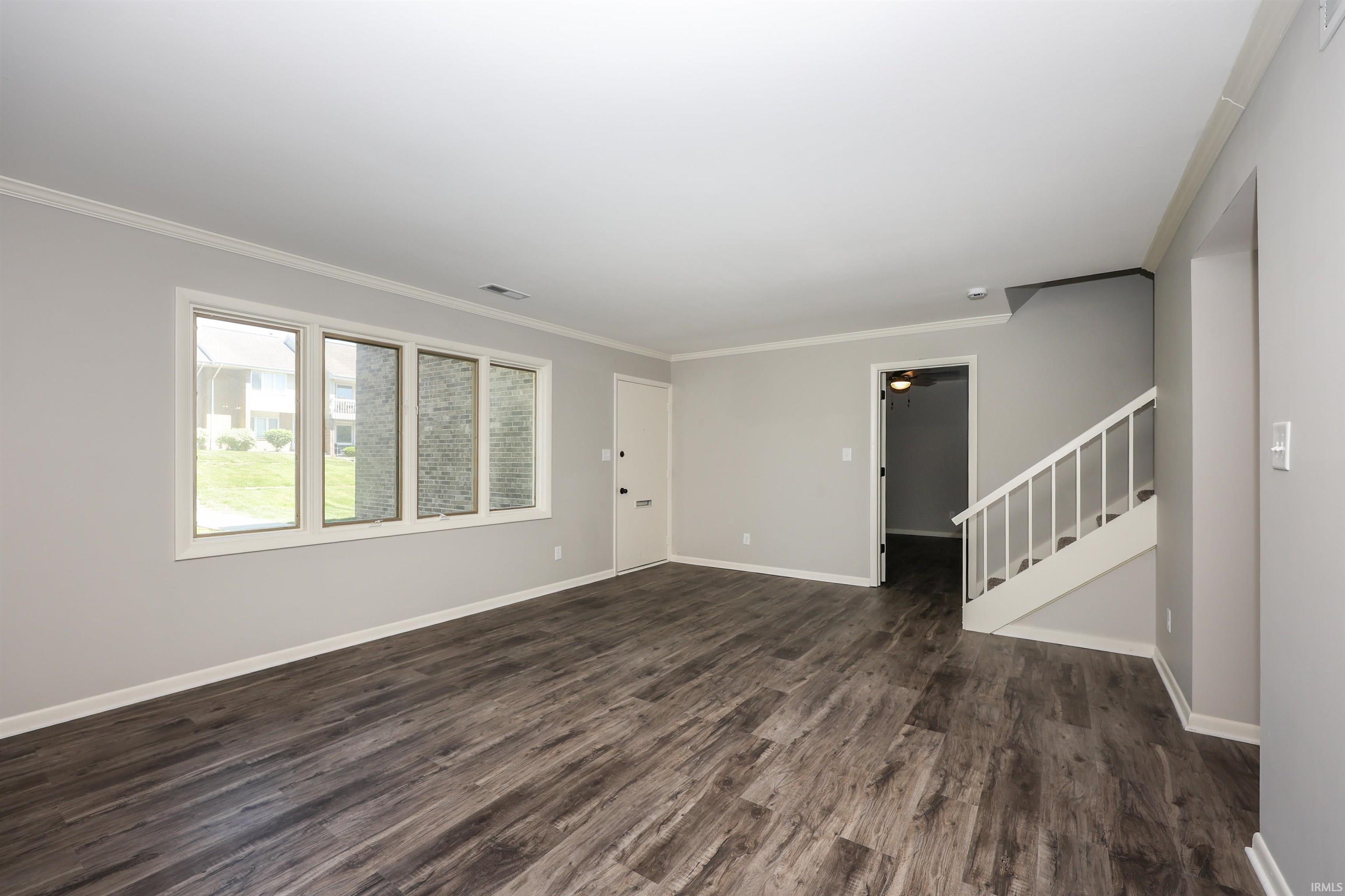 Spacious living area featuring wood-finish flooring and light grey walls