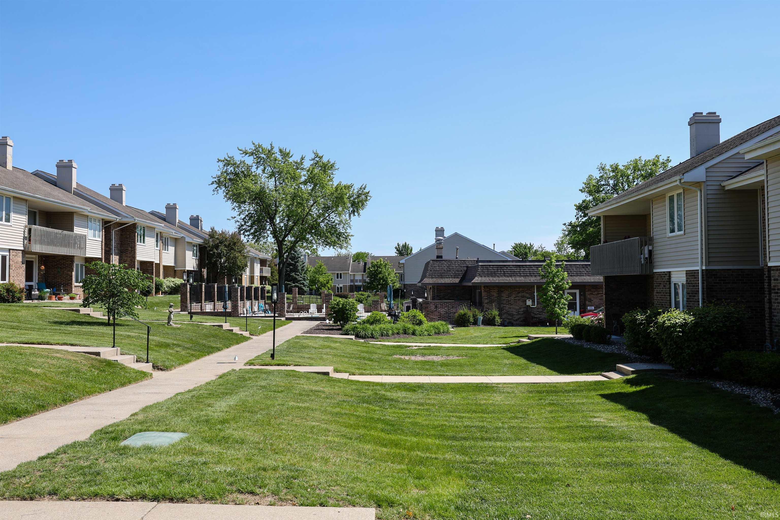 Expansive common area featuring manicured green spaces, concrete pathways, and mature trees