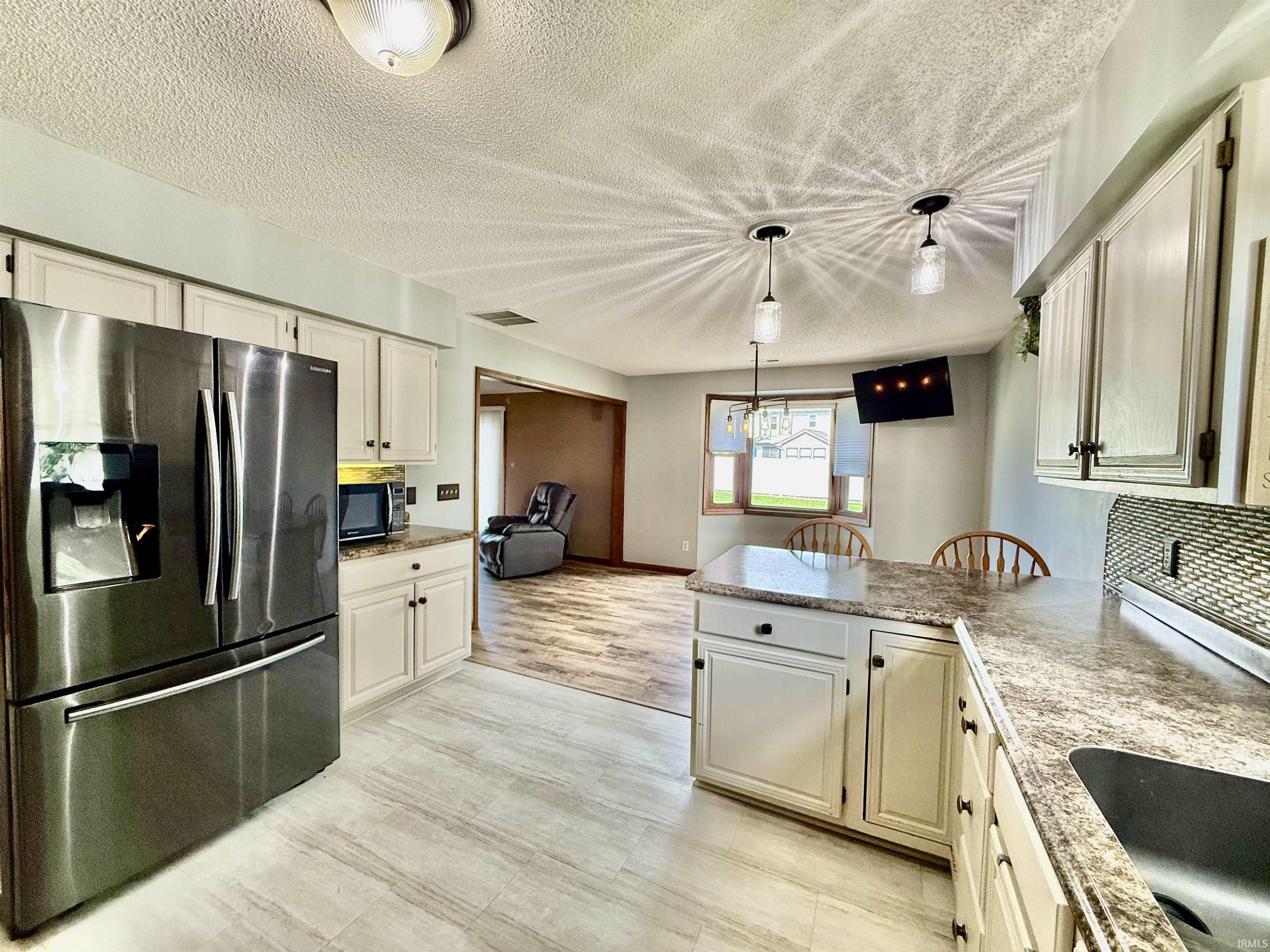 Kitchen featuring light wood-finish flooring, white cabinetry with dark hardware, and speckled countertops