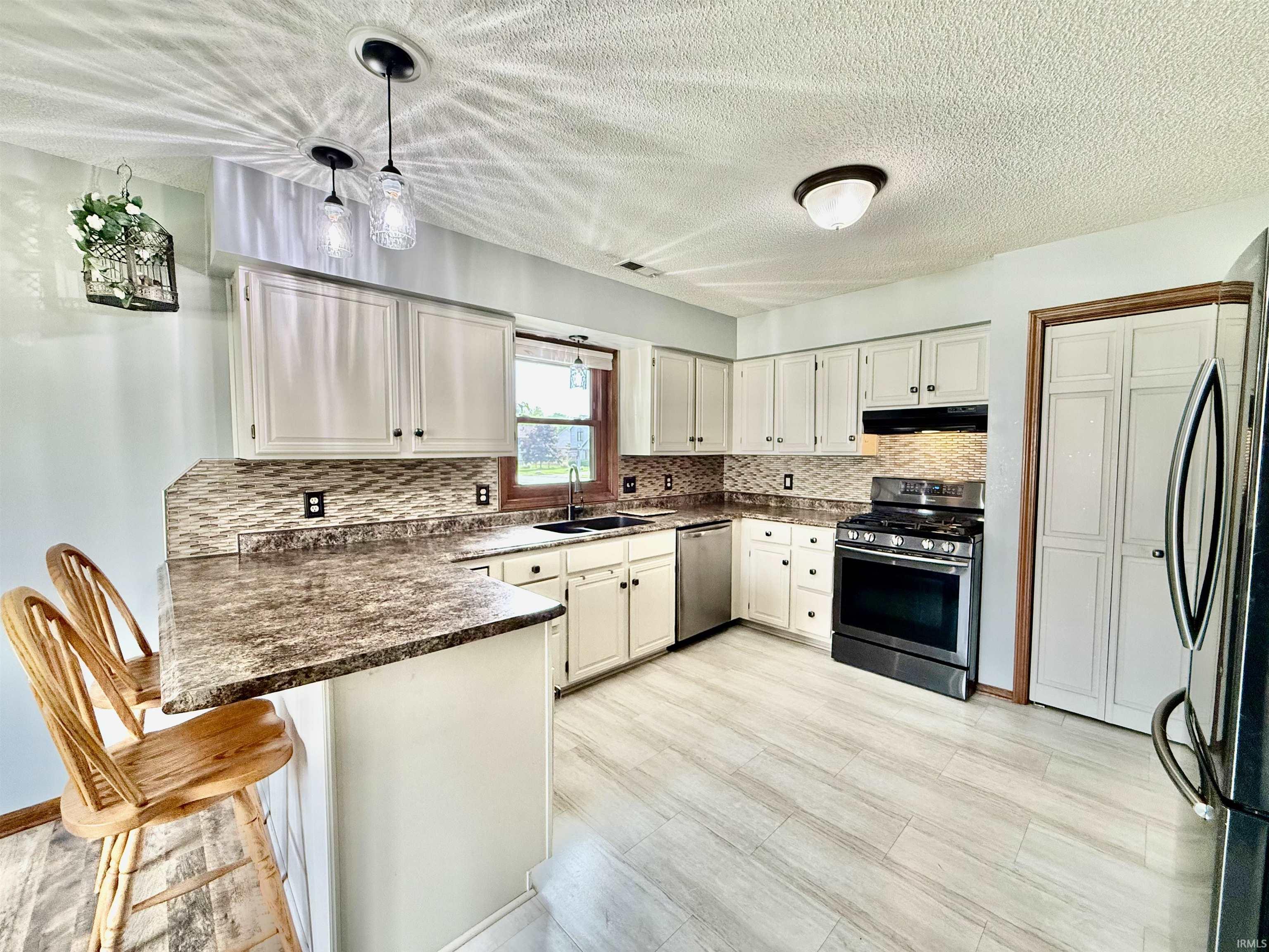 Kitchen featuring light-toned cabinetry, patterned tile backsplash, and wood-finish flooring