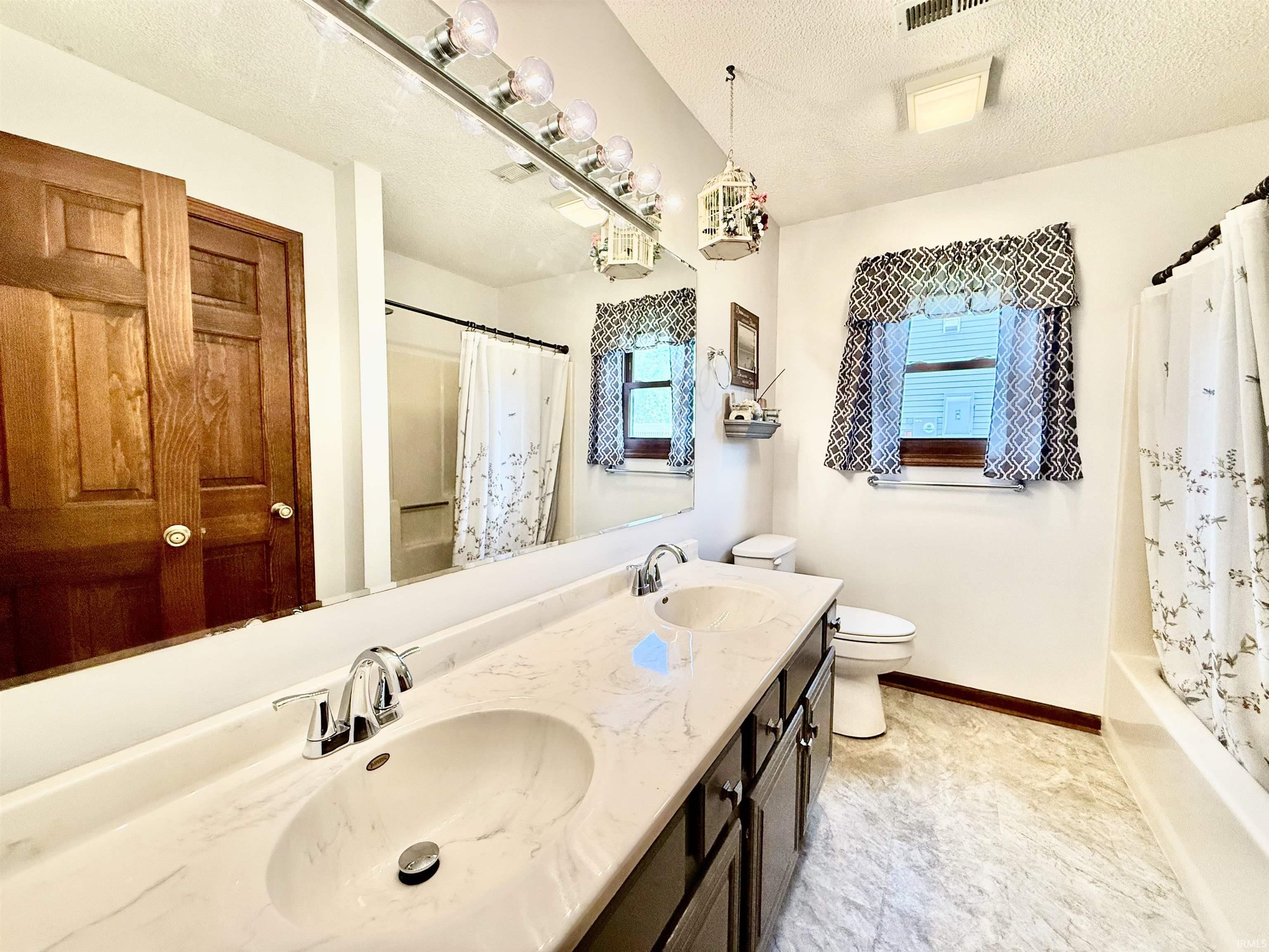 Bathroom featuring a dual vanity with a light-toned countertop, two integrated sinks, and chrome faucets