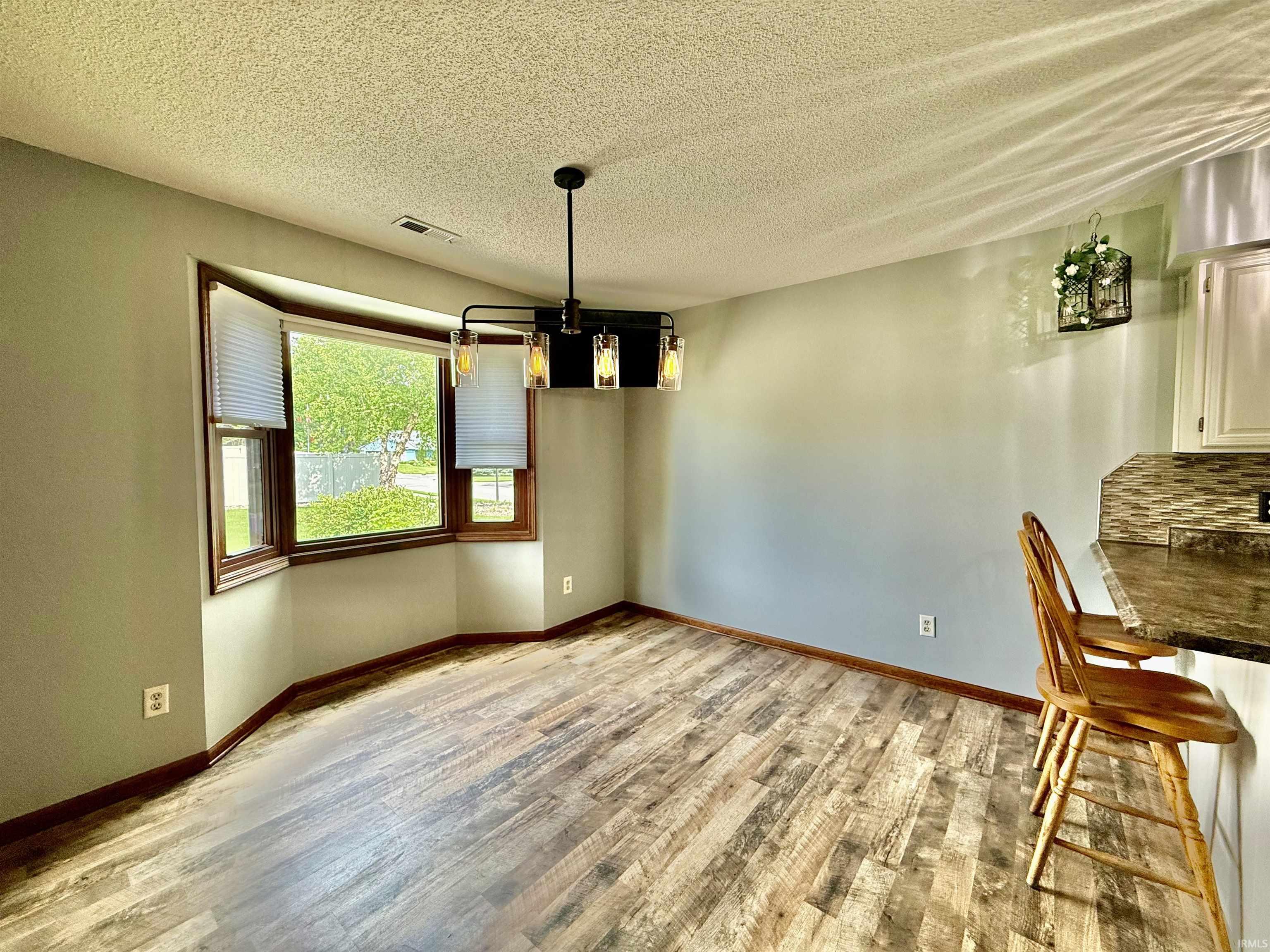 Dining area featuring wood-finish flooring and a bay window with blinds