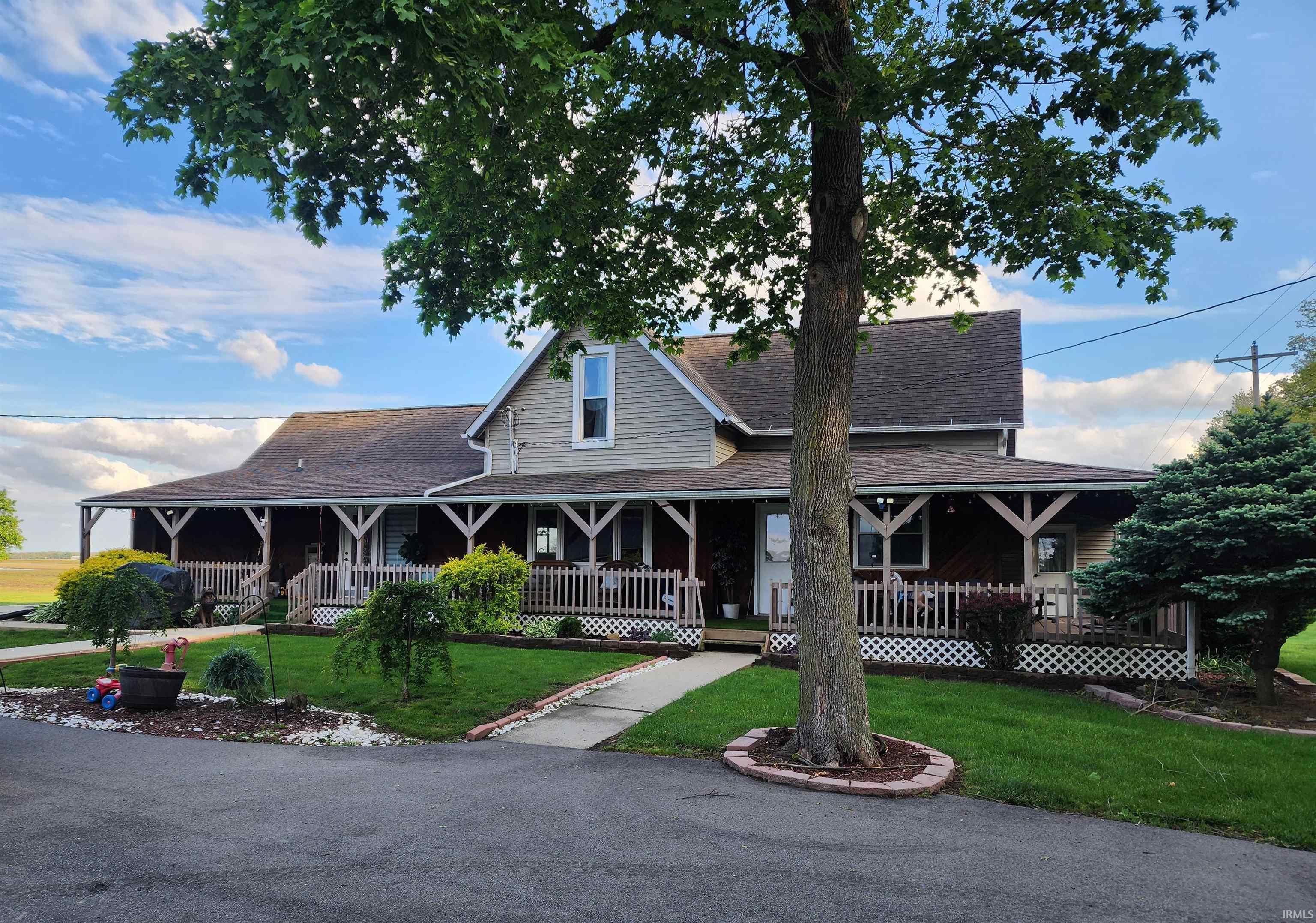 Property exterior featuring a full-width wraparound porch with lattice skirting and wood railings