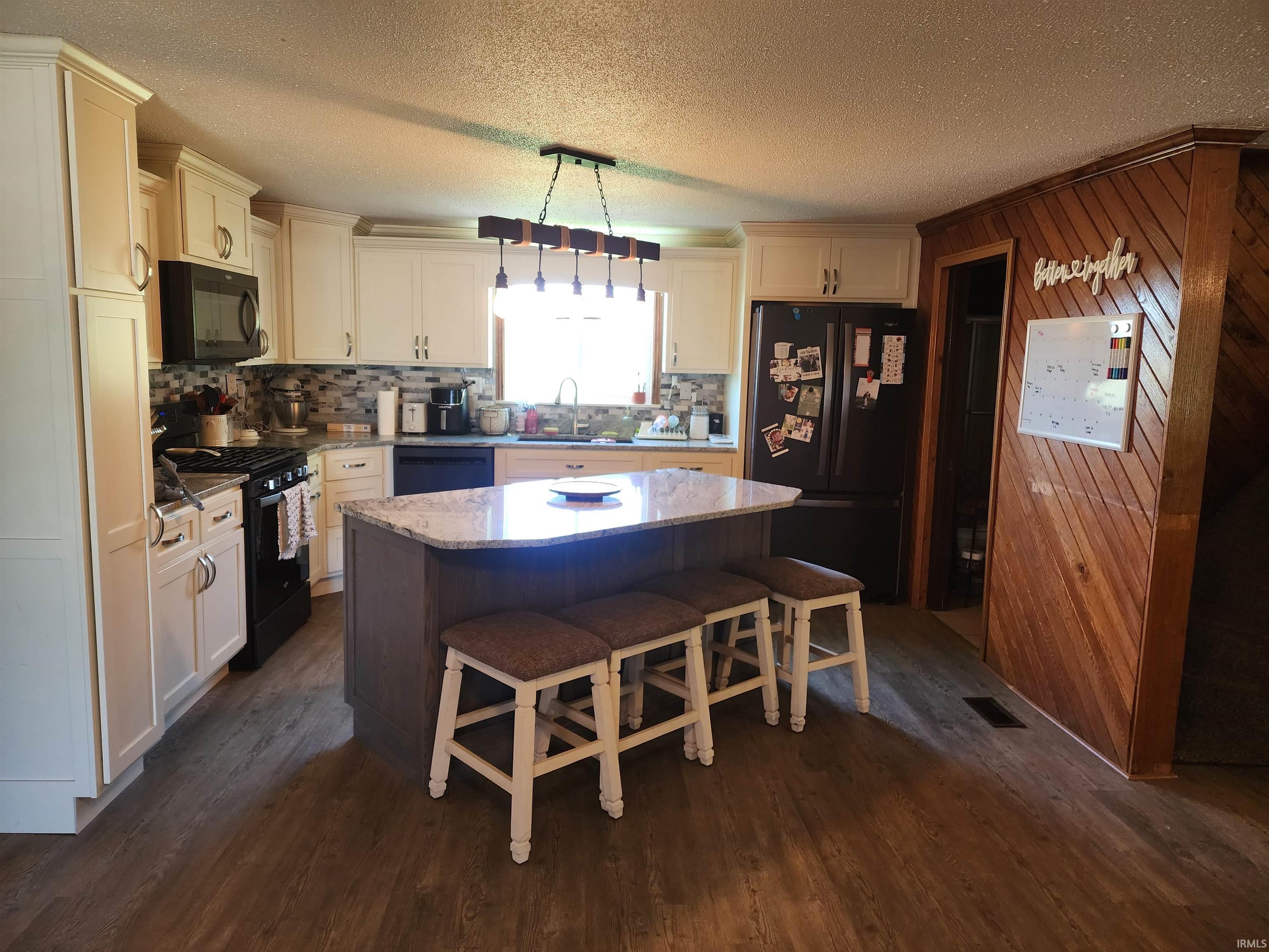 Kitchen featuring light-toned cabinetry, a mosaic tile backsplash, and a central island with a granite-style countertop