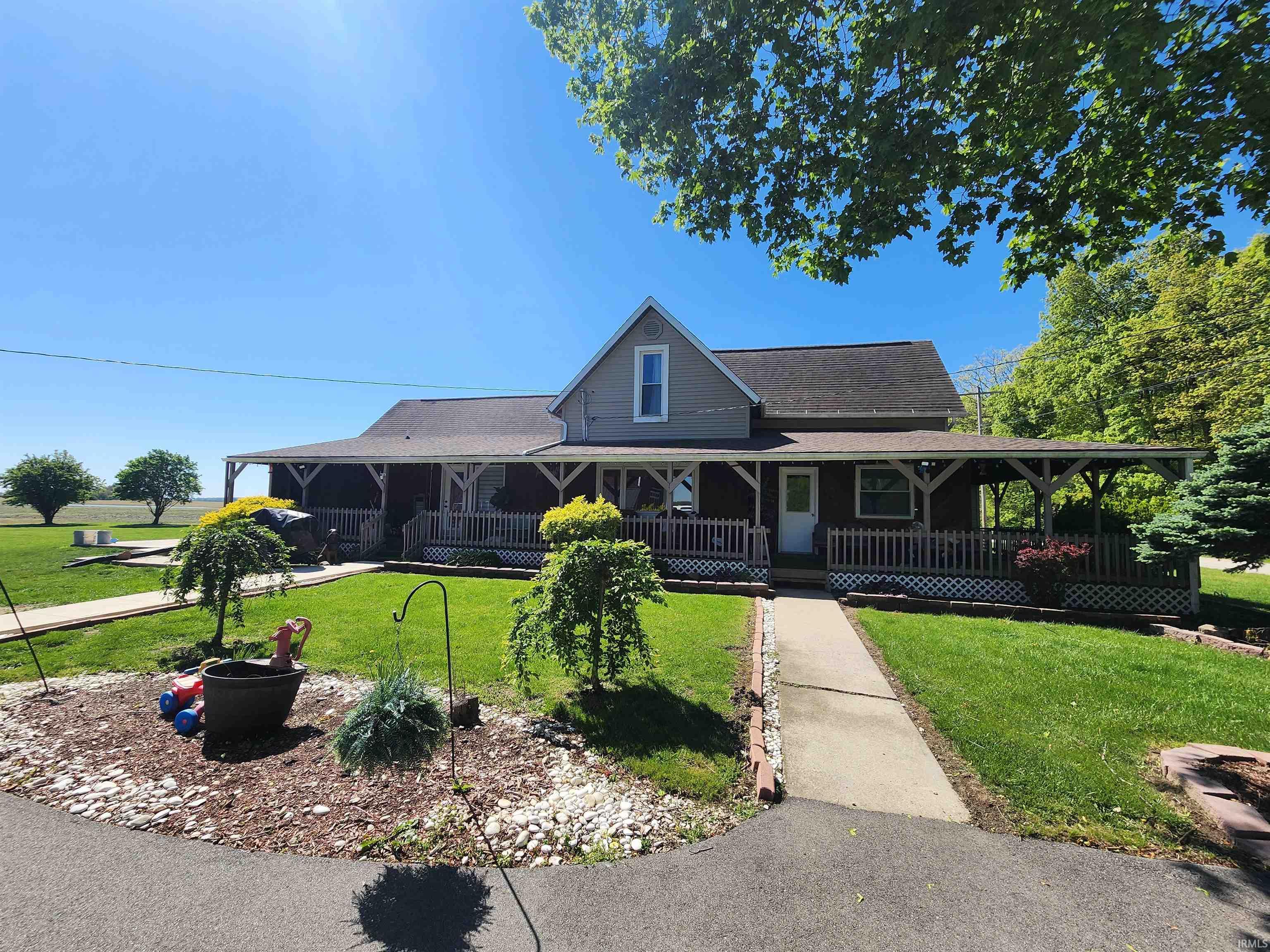 Expansive home exterior featuring a wrap-around porch with white lattice detailing, a gravel landscape bed, and a concrete walkway