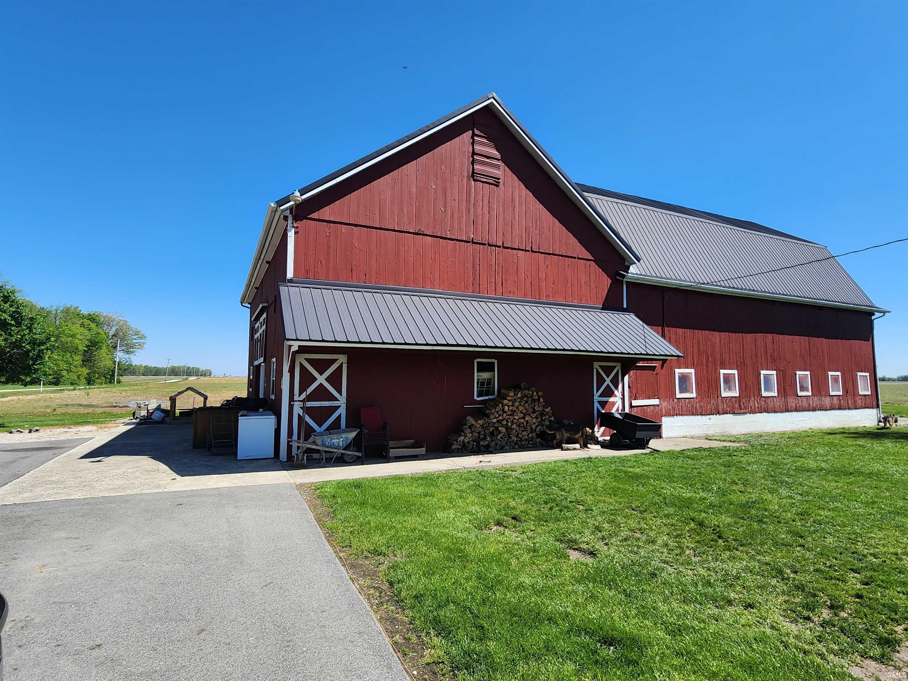 Red barn structure featuring a gabled roof with metal panels and white trim