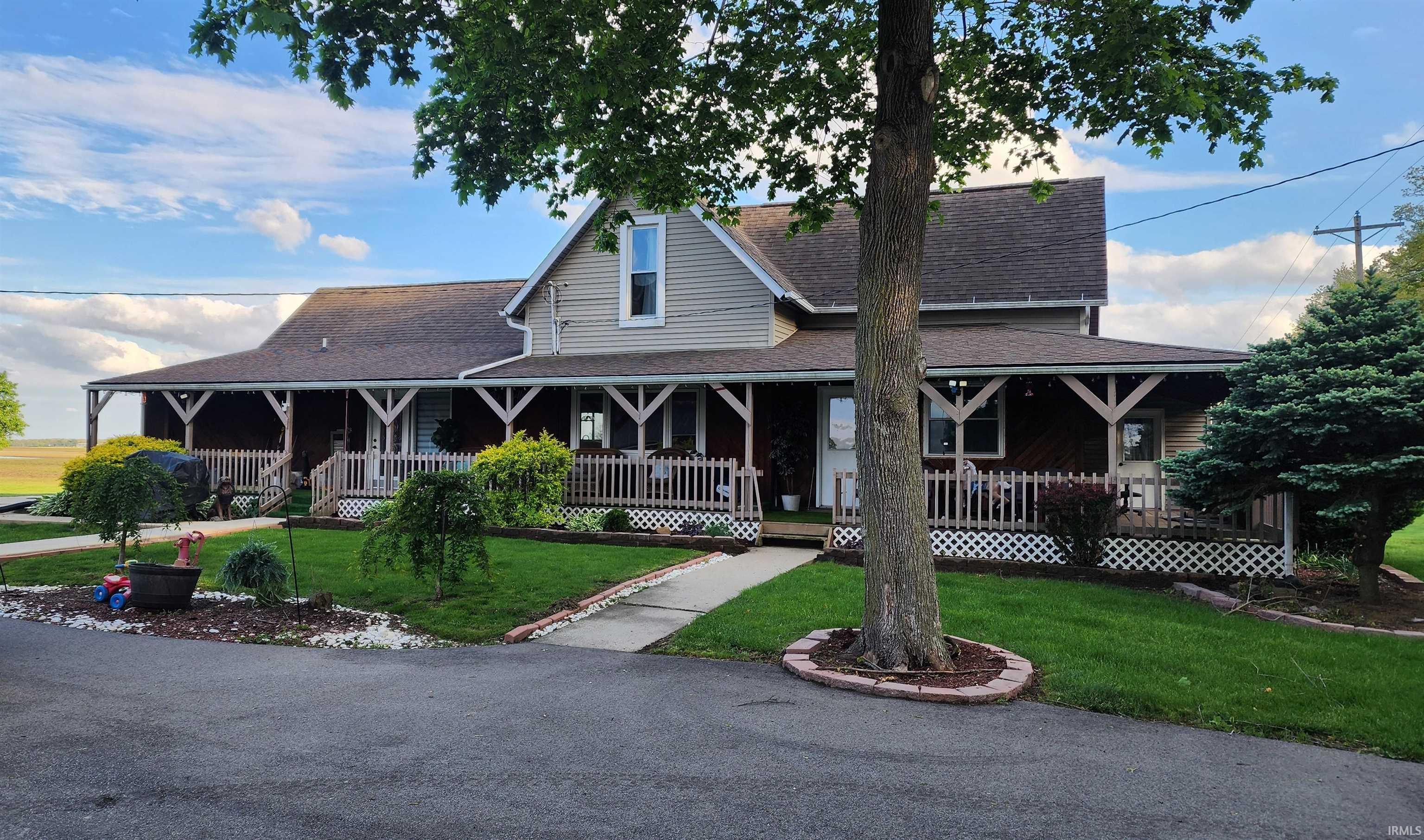 Two-story residence featuring a full-length covered front porch with white railings and lattice accents