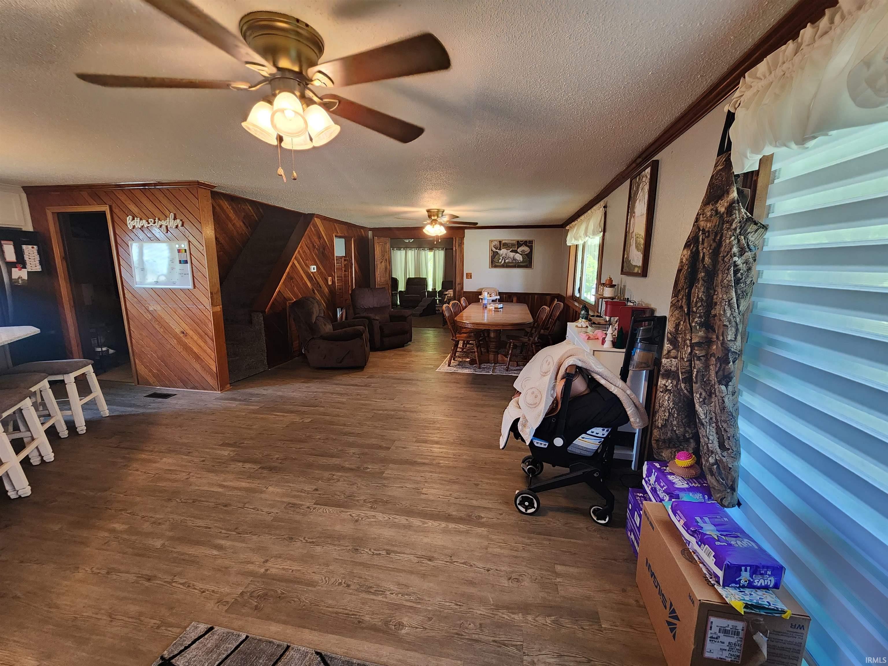 Spacious interior featuring wood-finish flooring, wood paneled walls, and multiple ceiling fans