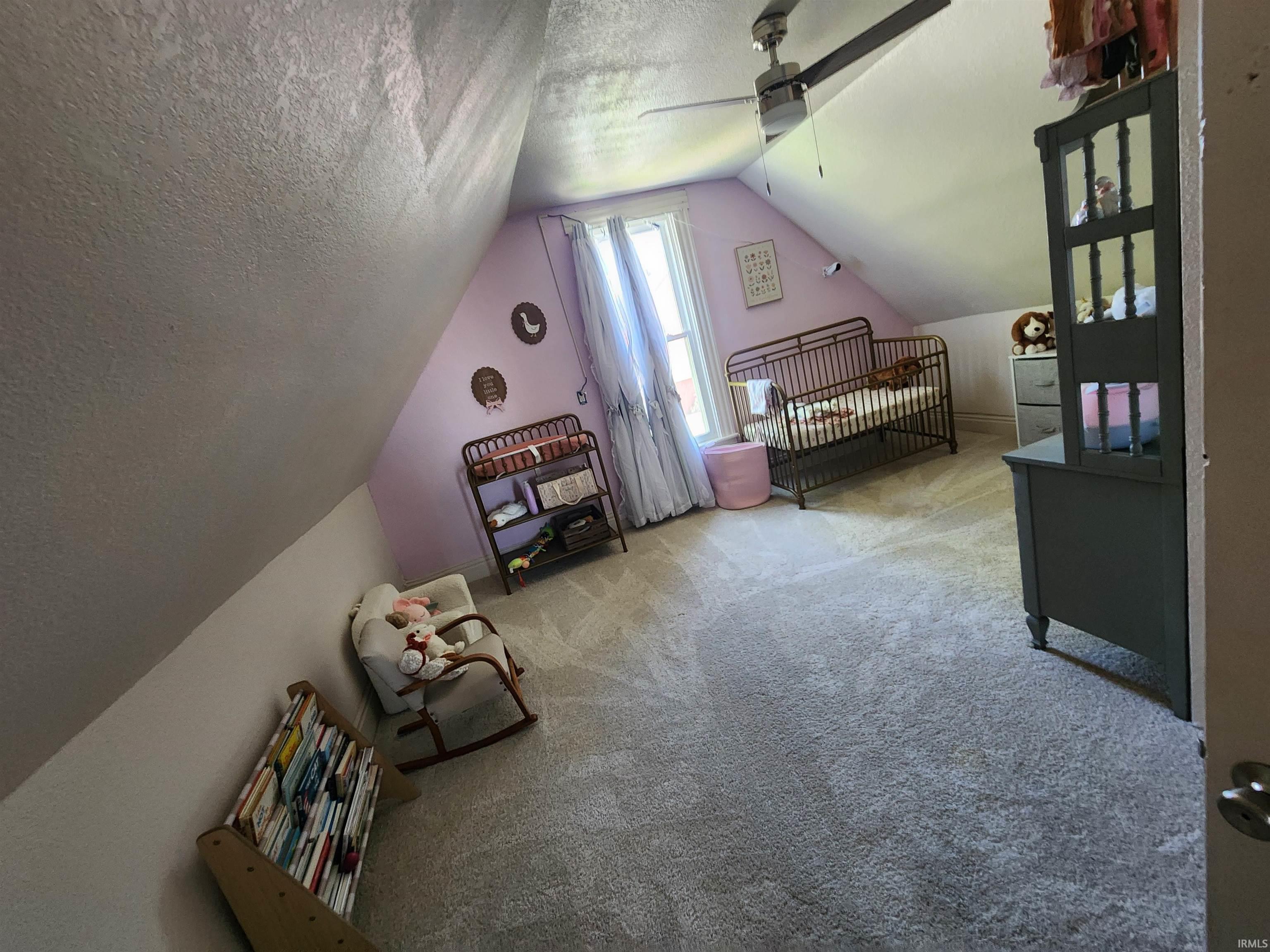 Carpeted room with sloped ceilings and a ceiling fan