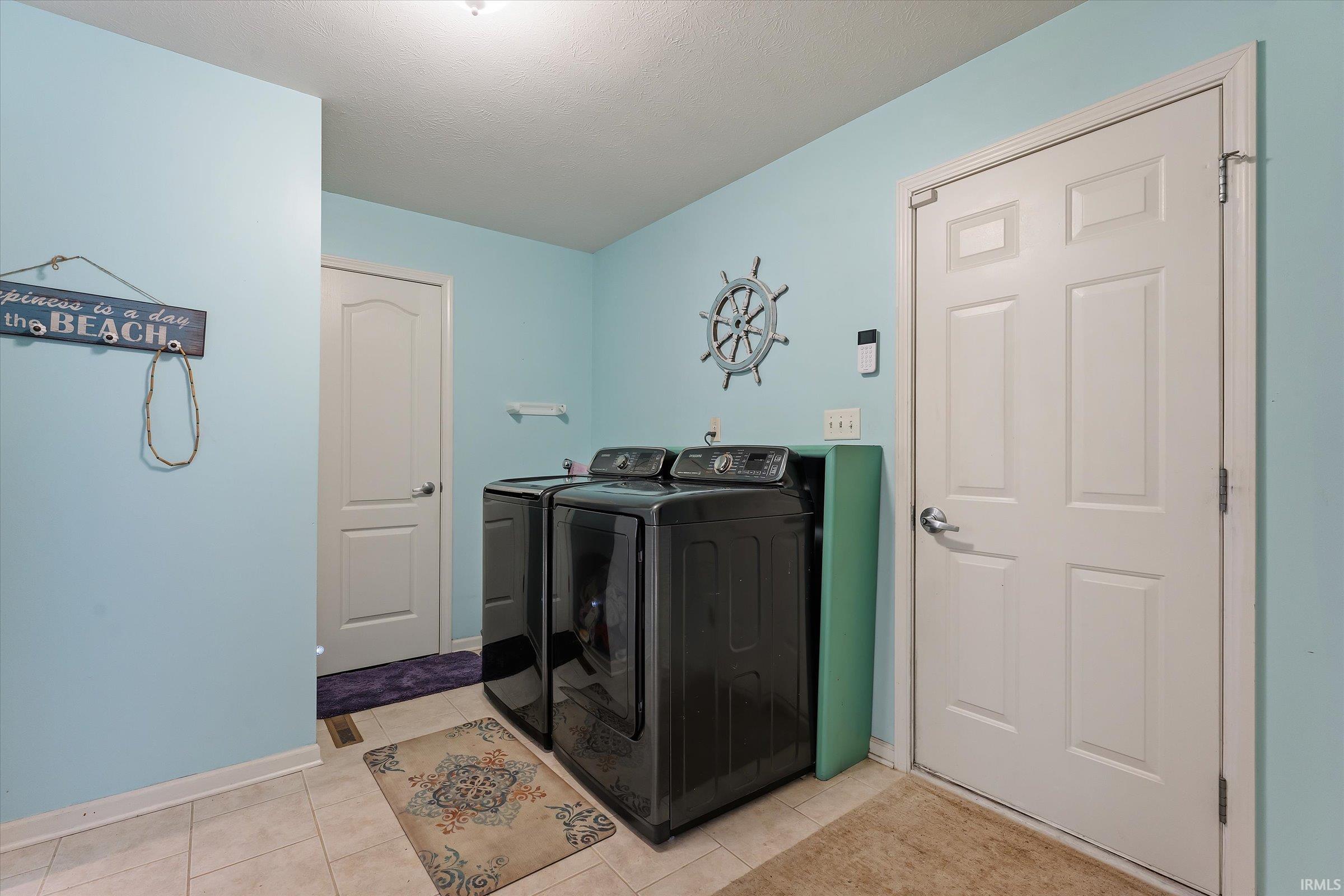 Laundry area with light blue walls and neutral tile flooring
