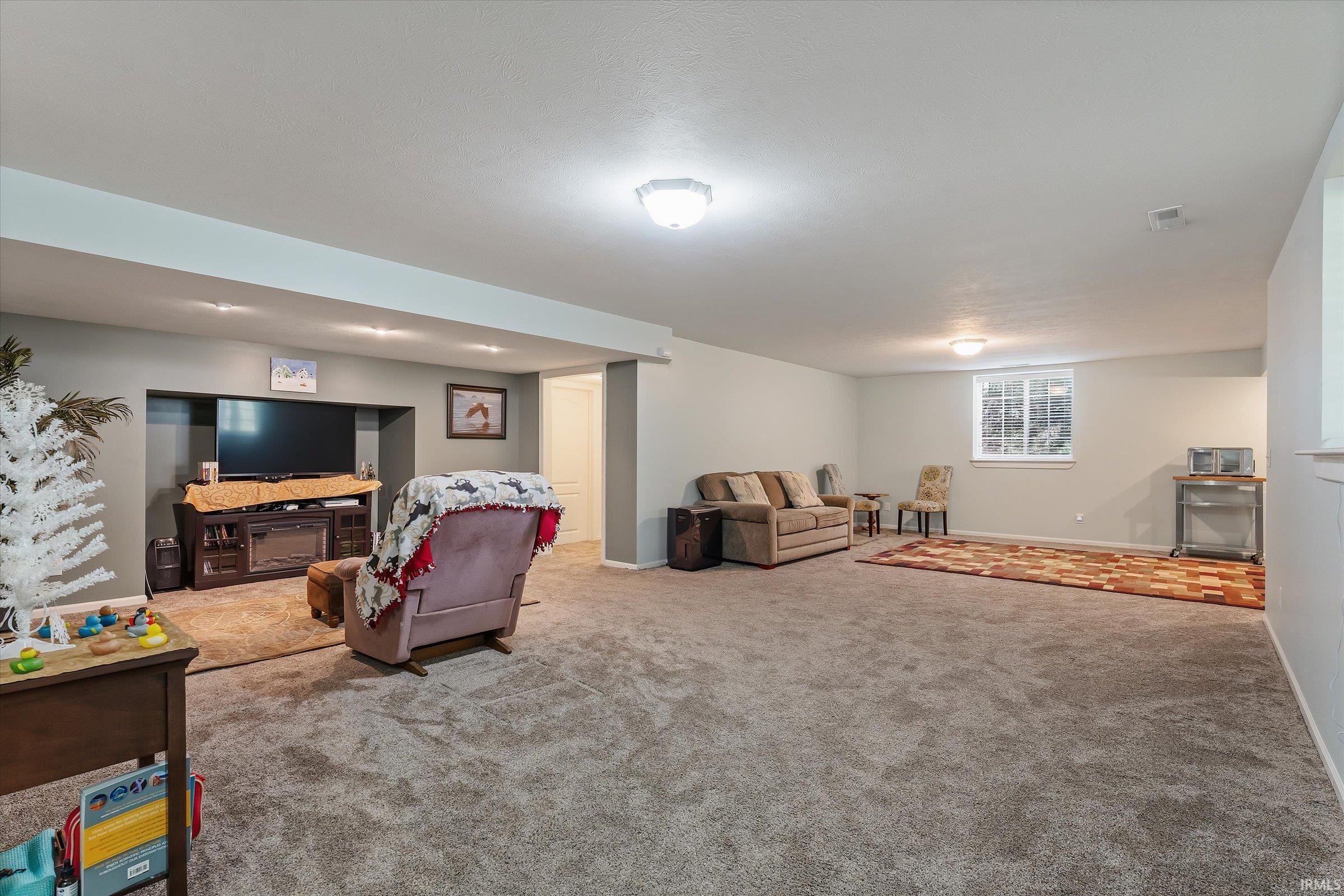Spacious lower-level room featuring light gray wall paint, recessed lighting, and neutral carpet flooring
