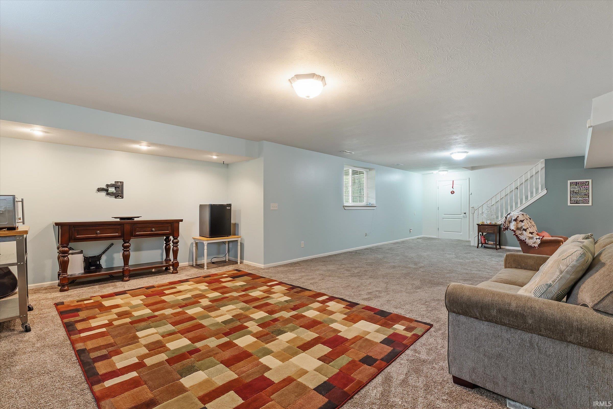 Spacious carpeted room featuring recessed lighting and a white staircase with balusters