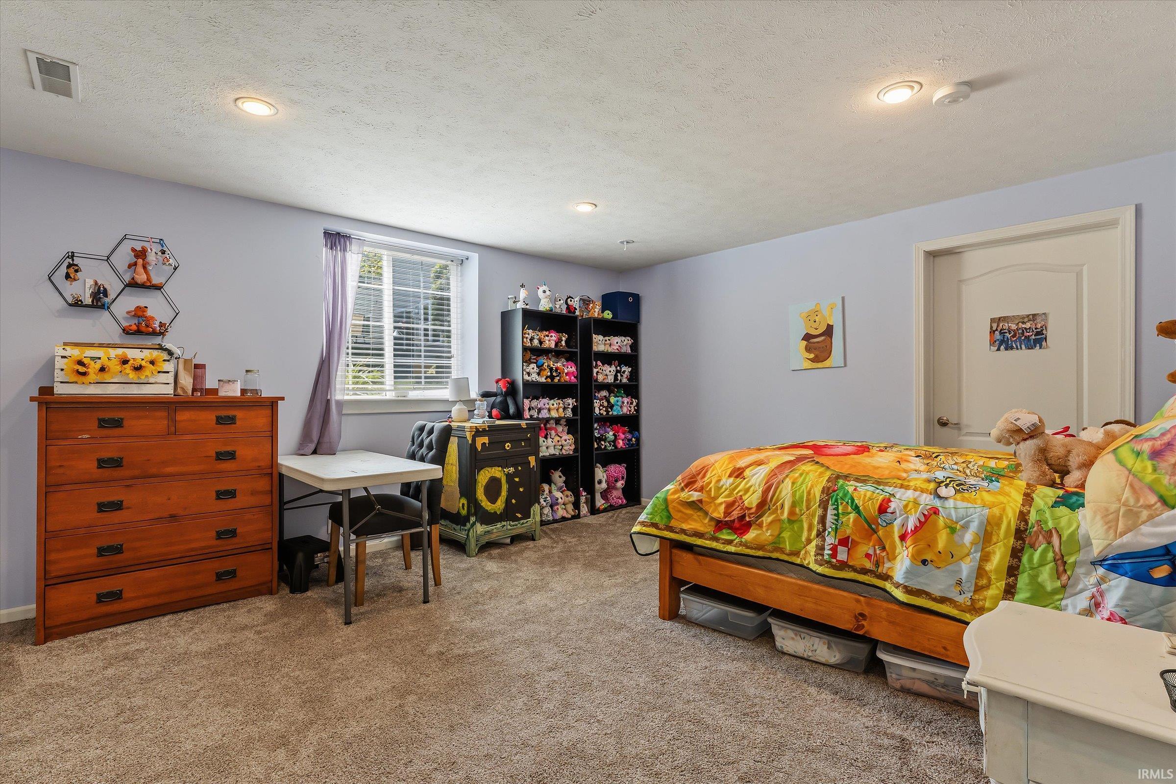 Carpeted room featuring a single window with blinds, recessed lighting, and a paneled door