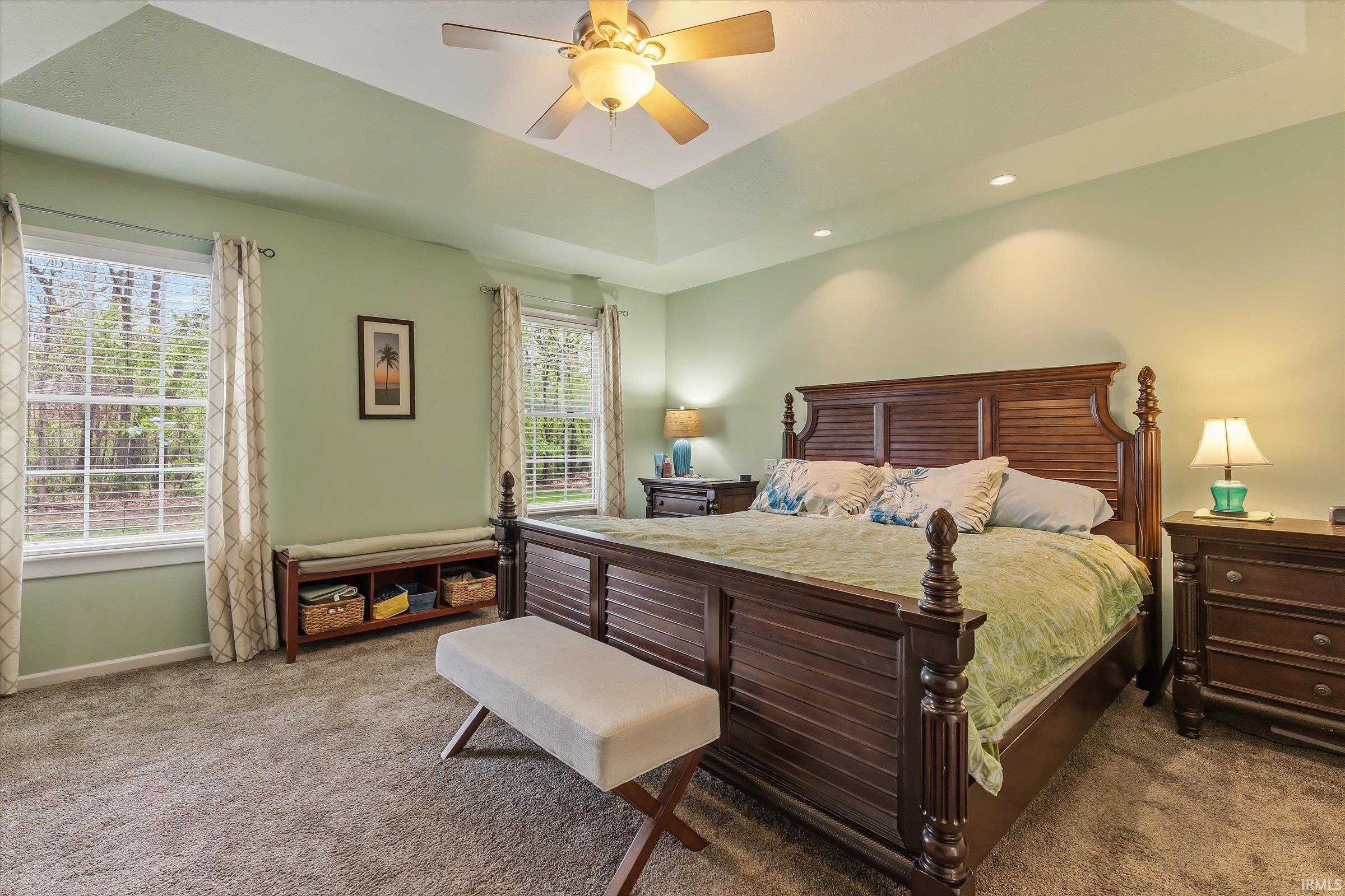 Spacious room featuring a tray ceiling with a ceiling fan, recessed lighting, and soft green walls