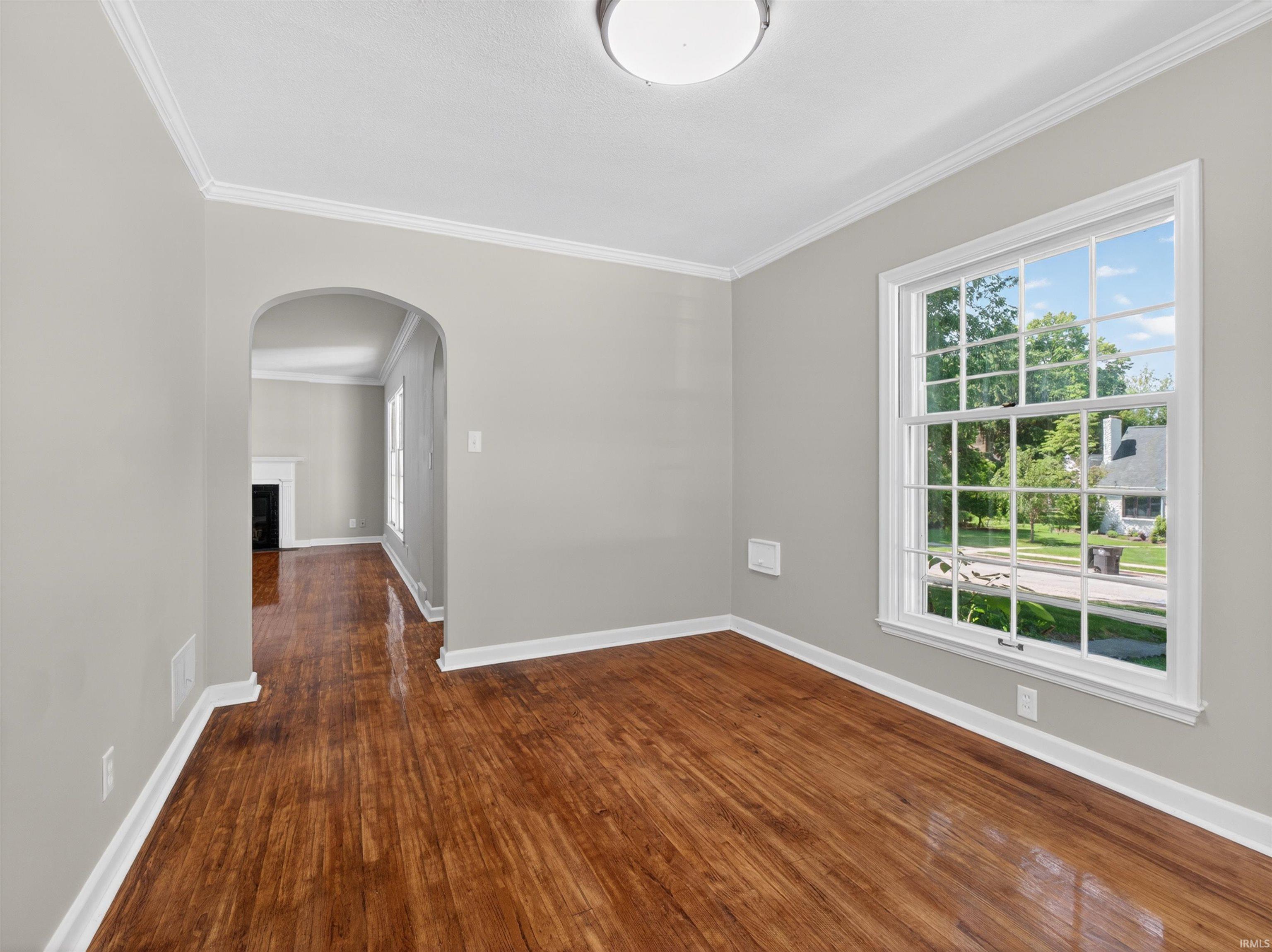 Hardwood-finish flooring throughout, featuring an arched doorway and a large multi-pane window