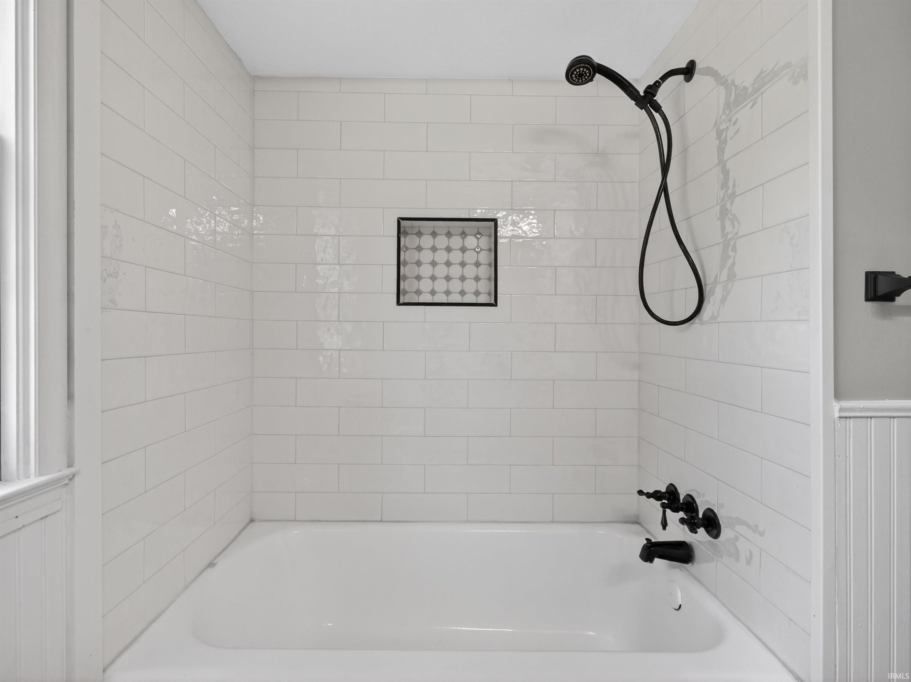 Bathtub and shower combination featuring white subway tile surround