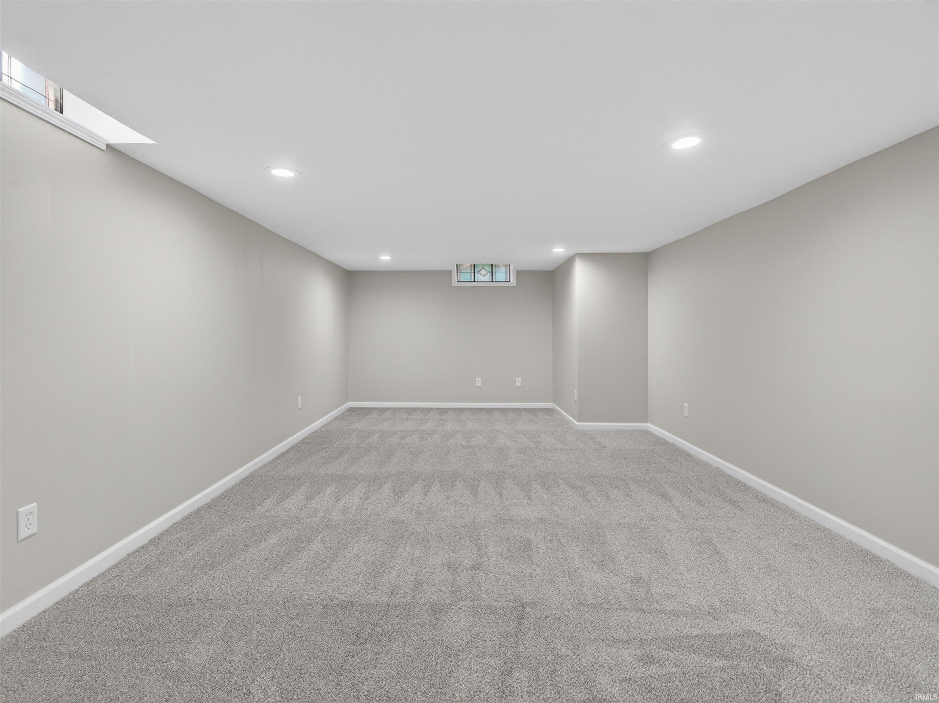 Spacious room featuring light gray carpeting, recessed ceiling lighting, and neutral wall paint
