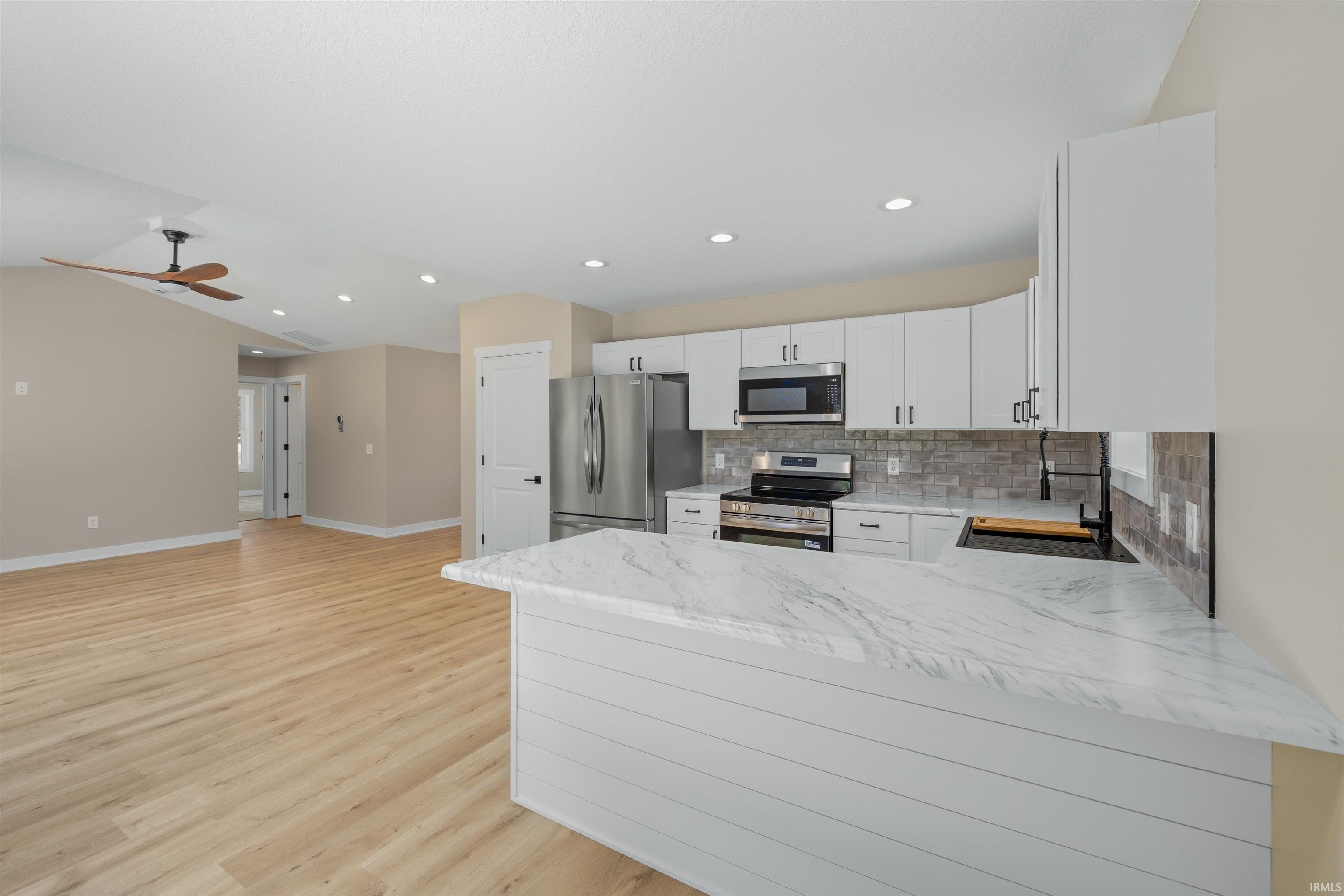 Contemporary kitchen featuring white cabinetry, stainless steel appliances, and a tiled backsplash