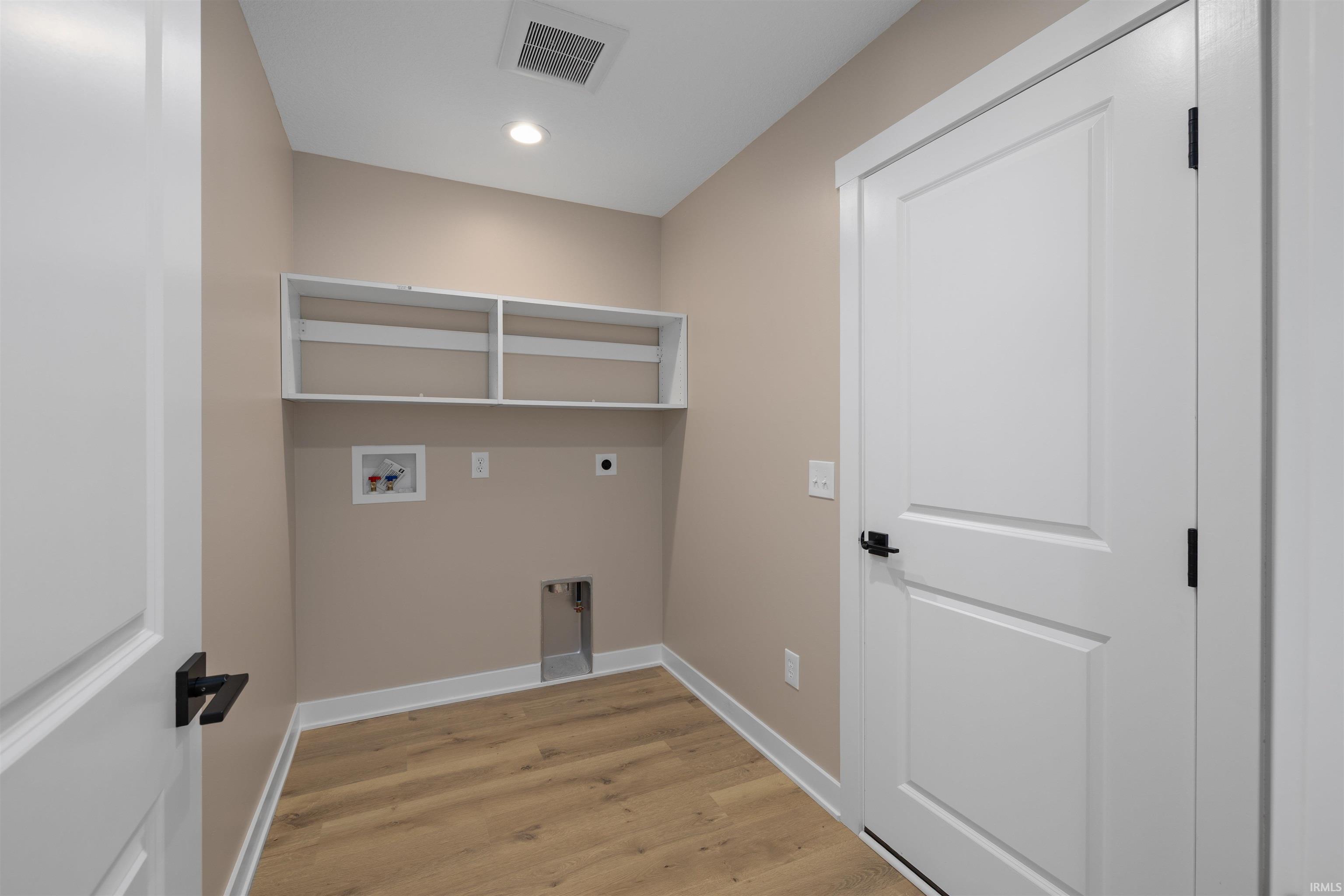 Dedicated utility room featuring wood-finish flooring, light beige walls, and white trim